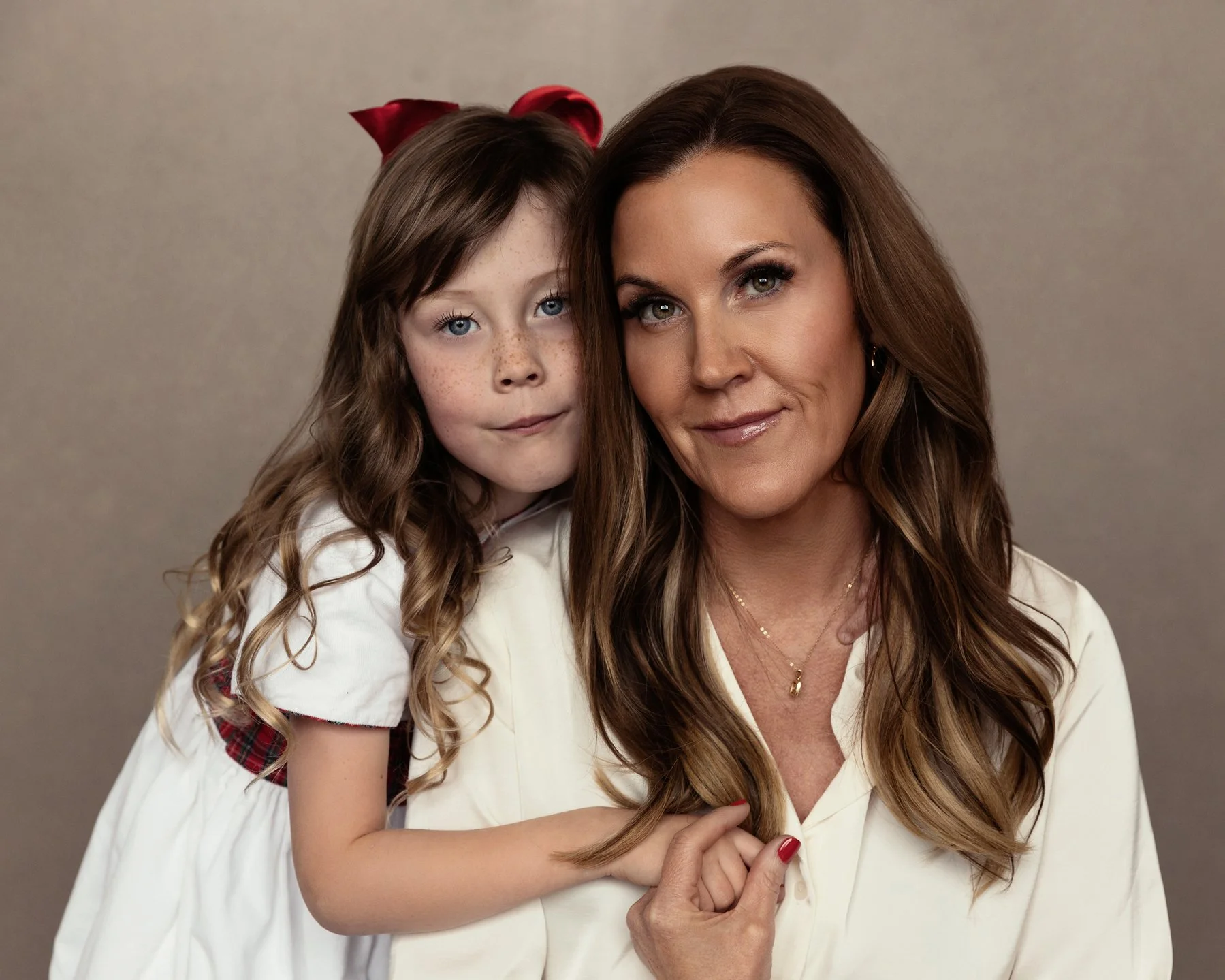  Mother and young daughter posing close together in soft neutral tones, capturing a tender and intimate moment in a family photography session. 