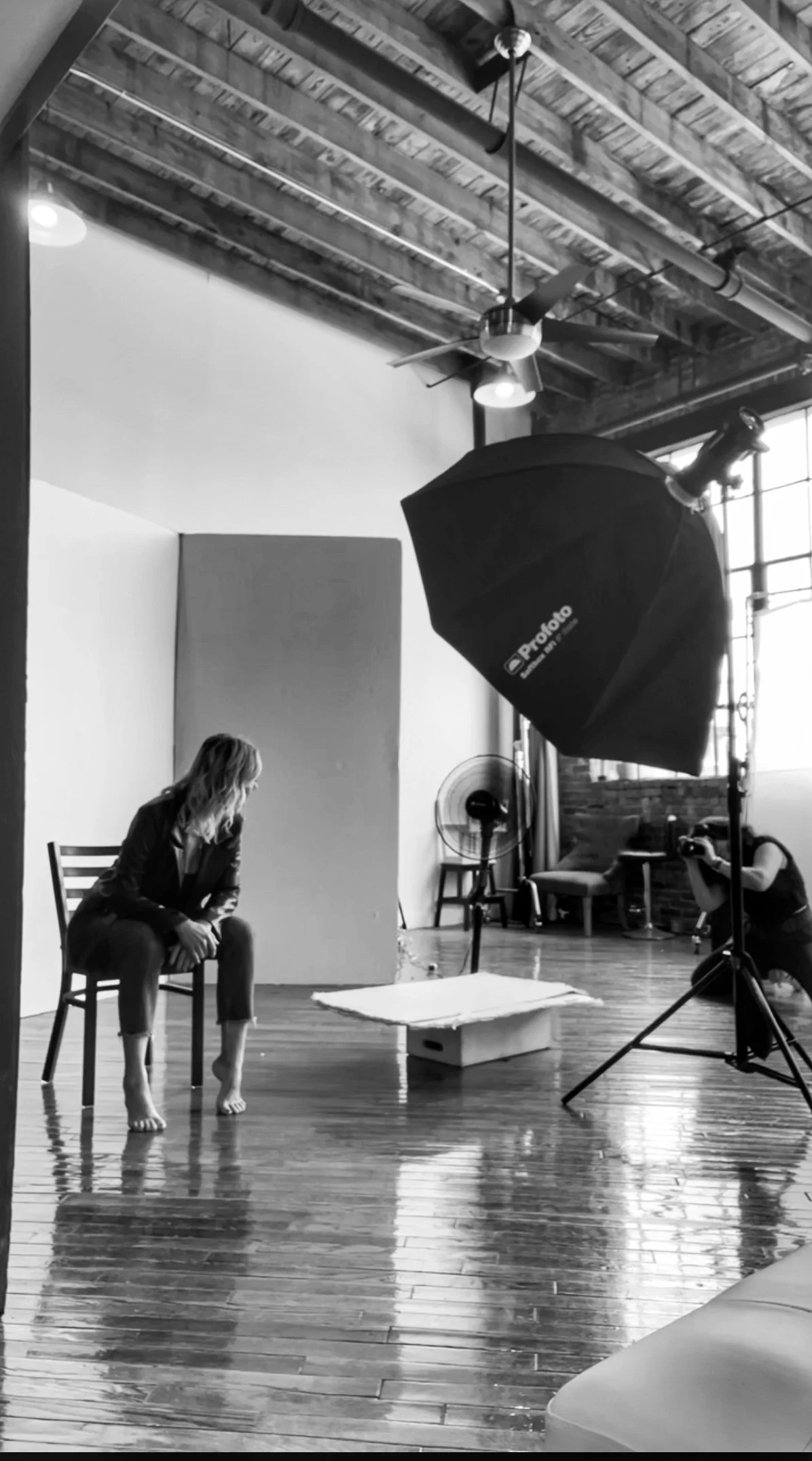  Black and white BTS shot of Judith shooting a photoshoot of a woman in her 40s. 