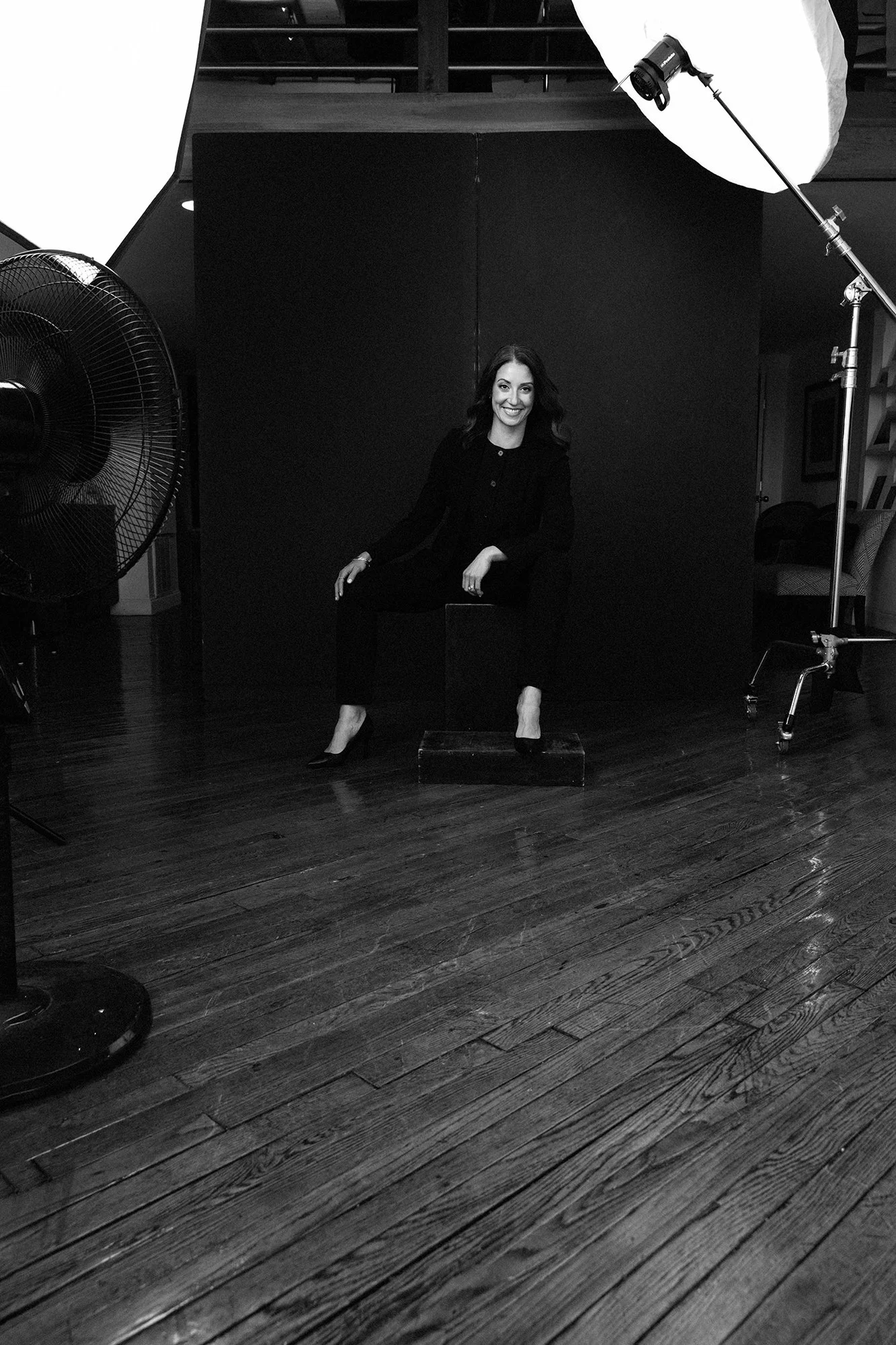  Black and white BTS shot of a woman in her 40s on set being photographed in Judith Hill’s Nashville Portrait Studio. 