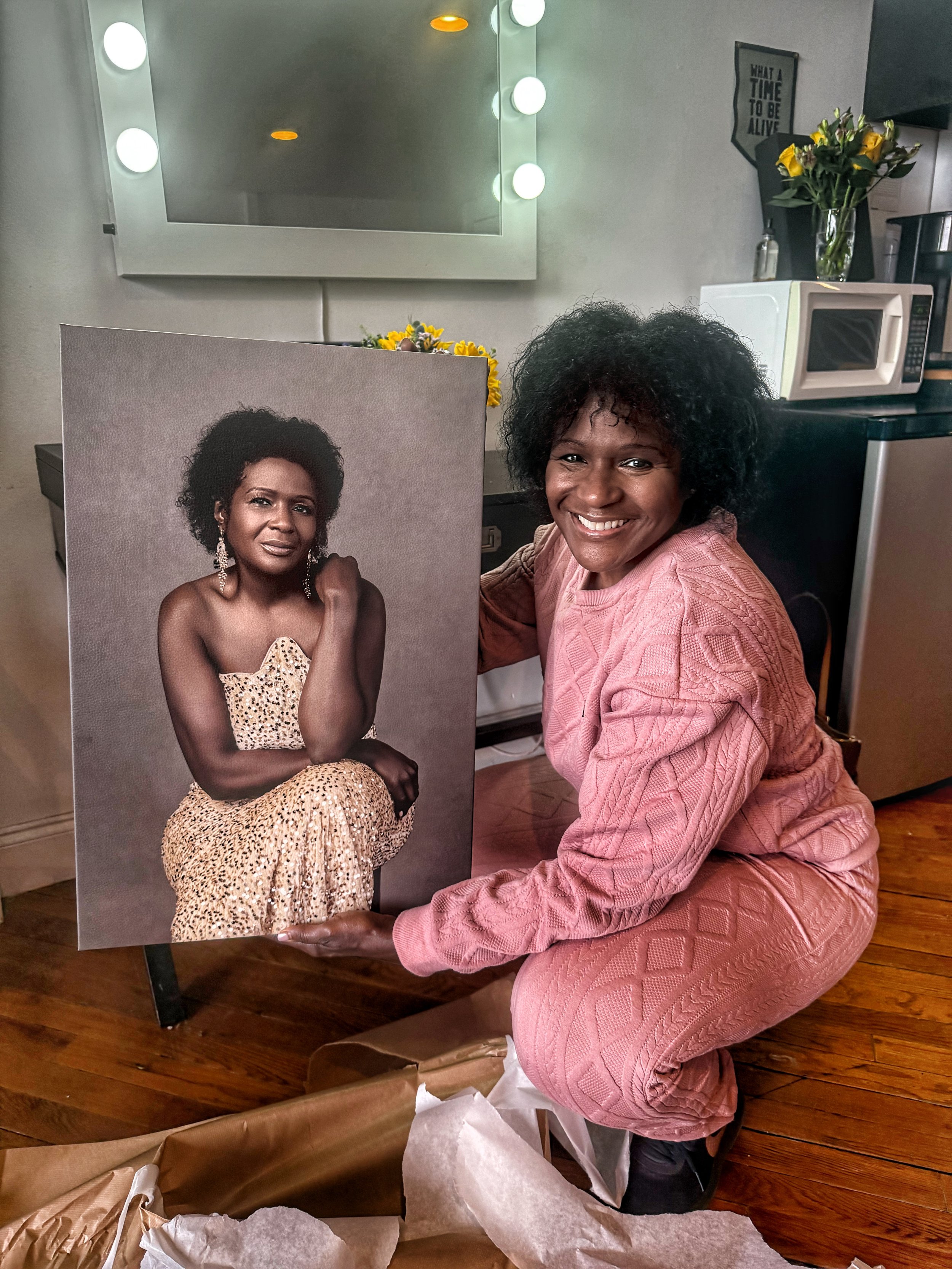  Black woman in her 40s holding the wall art of her portrait printed on leather that she purchased in Judith Hill Photography’s Nashville studio. 