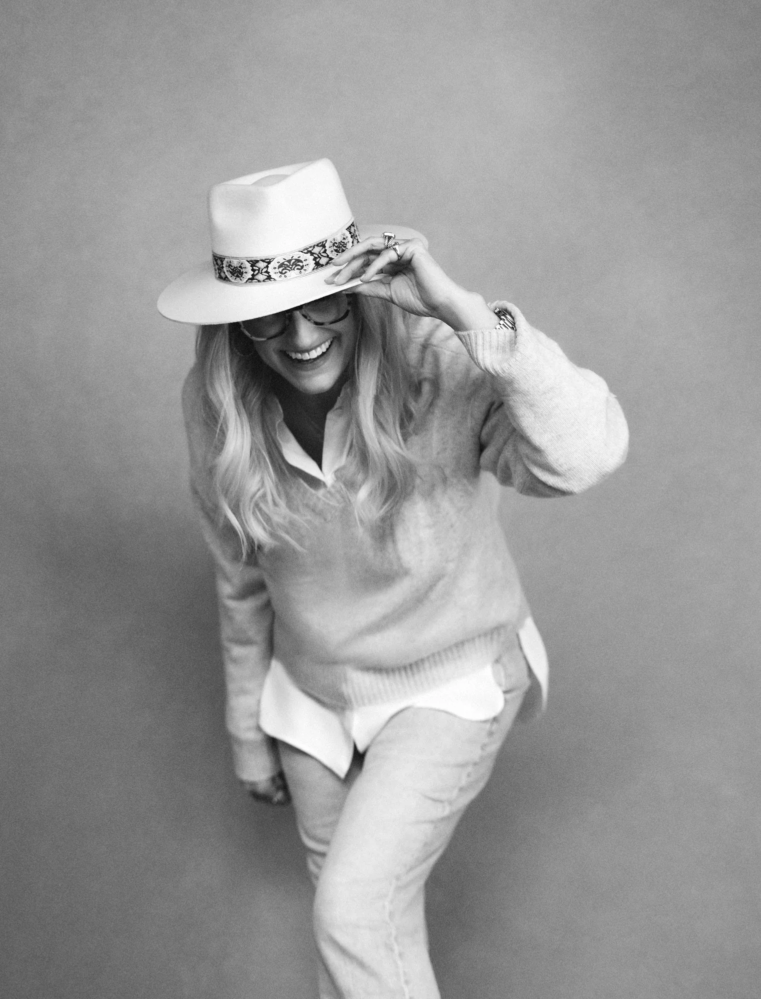  Black and white photo from above of a laughing woman tipping a felt hat, Nashville portrait session 