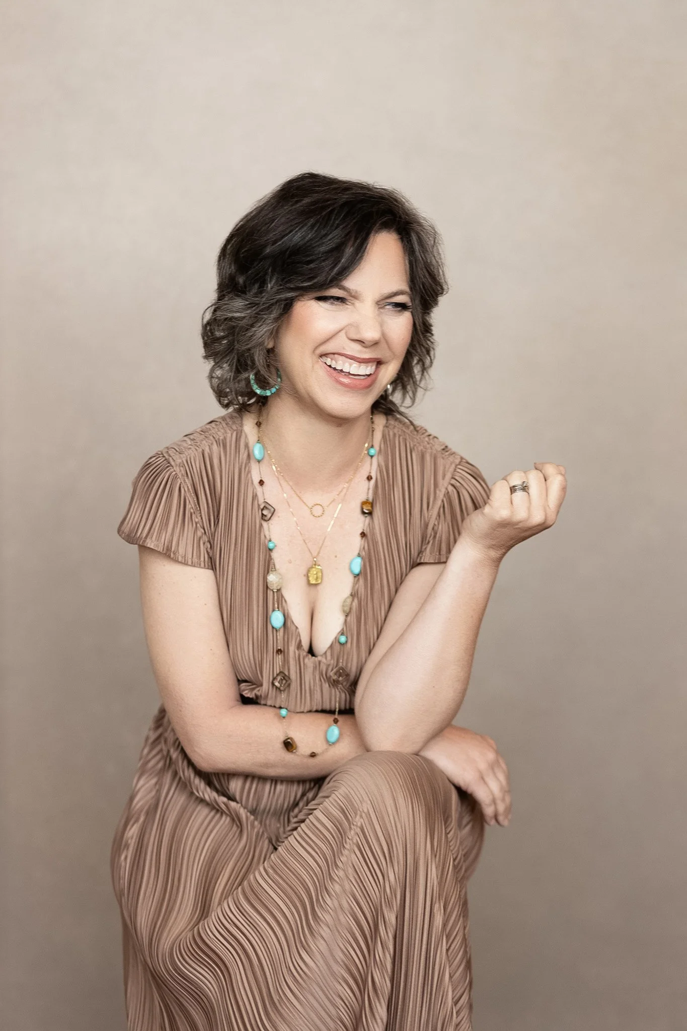 Woman laughing in a taupe dress with turquoise jewelry, Nashville studio portrait by Judith Hill