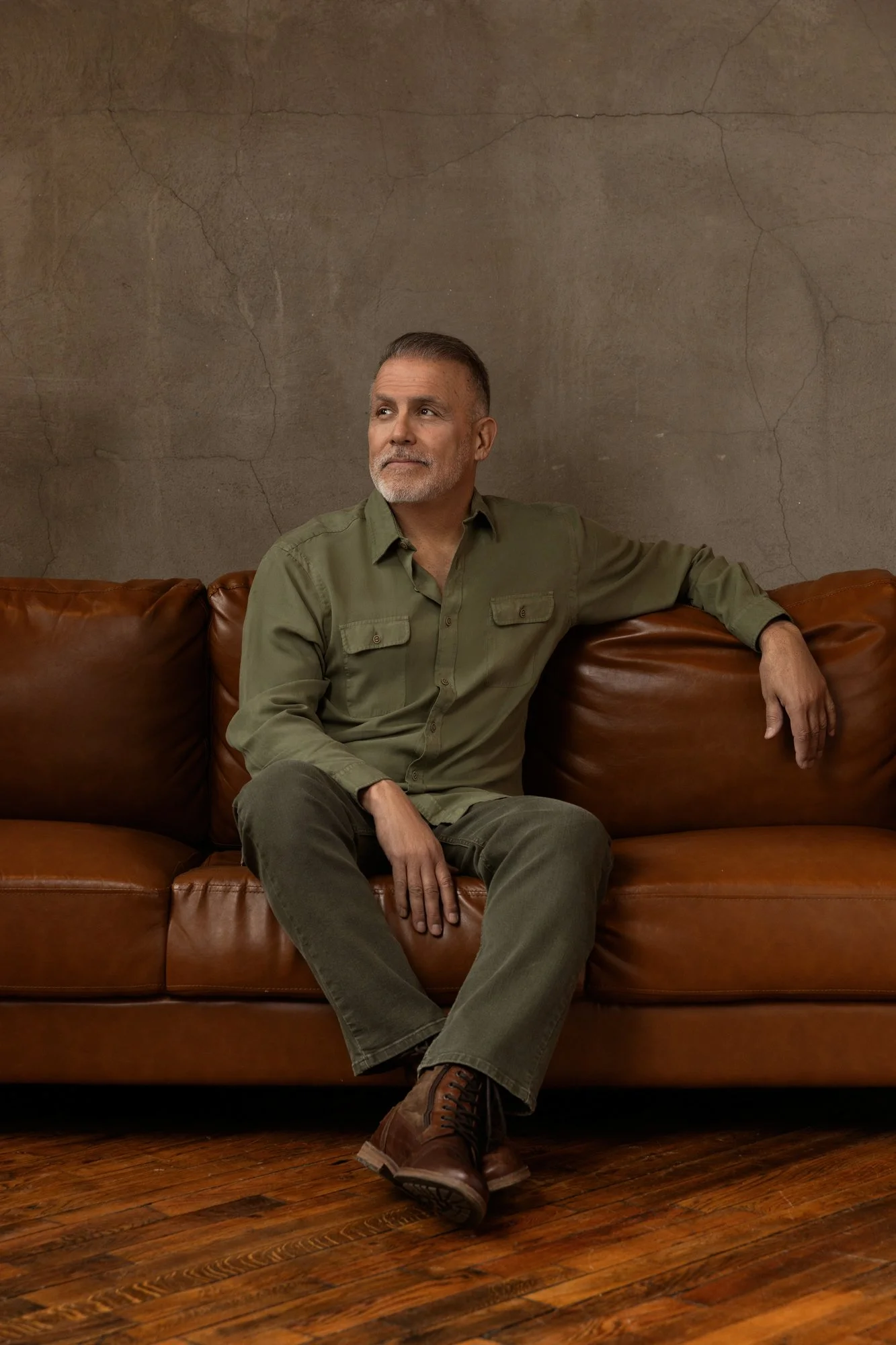 Man in an olive shirt seated on a brown leather sofa, Nashville men's portrait by Judith Hill