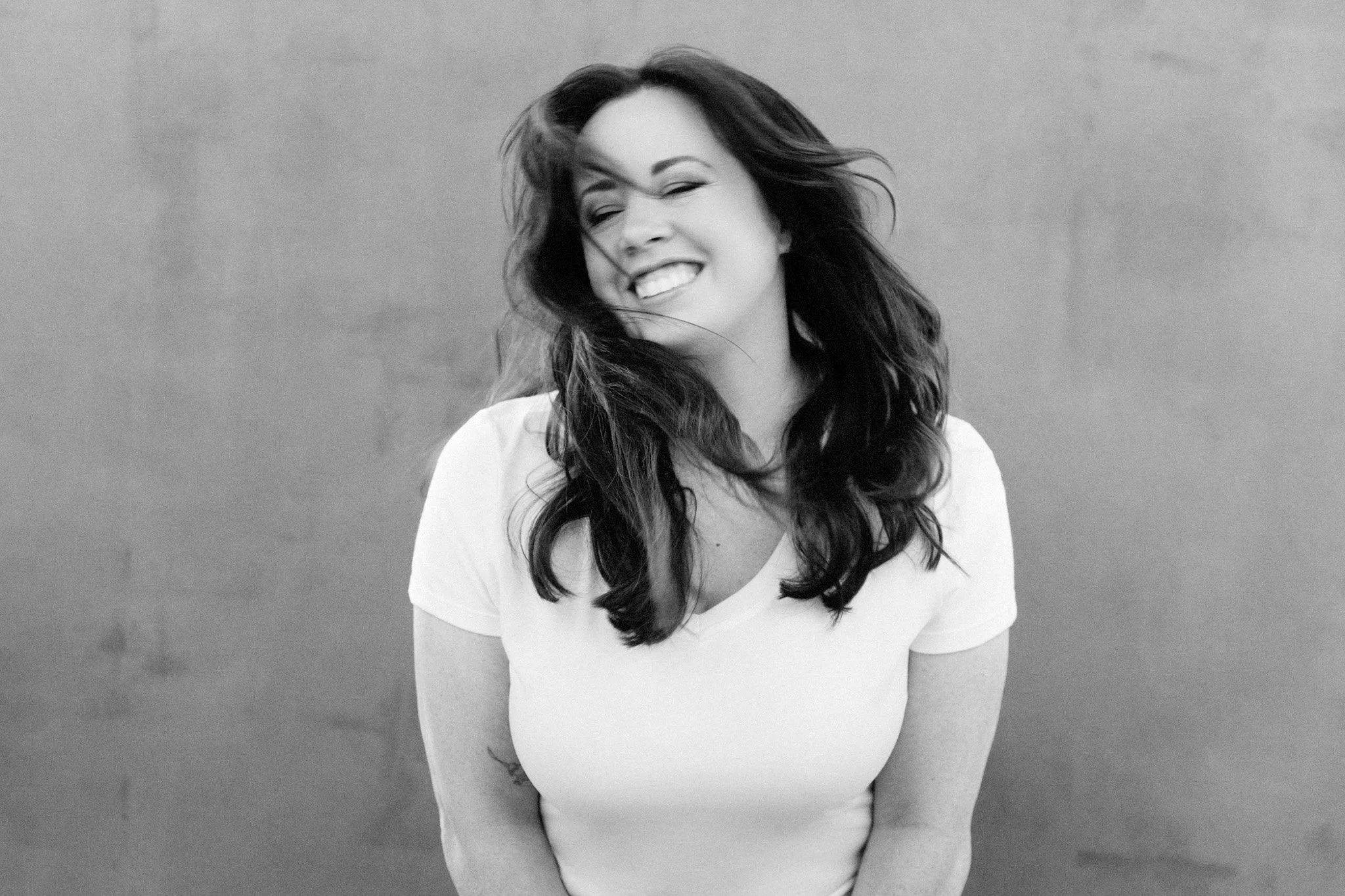 Black-and-white portrait of a woman laughing in a white tee, Nashville candid portrait by Judith Hill