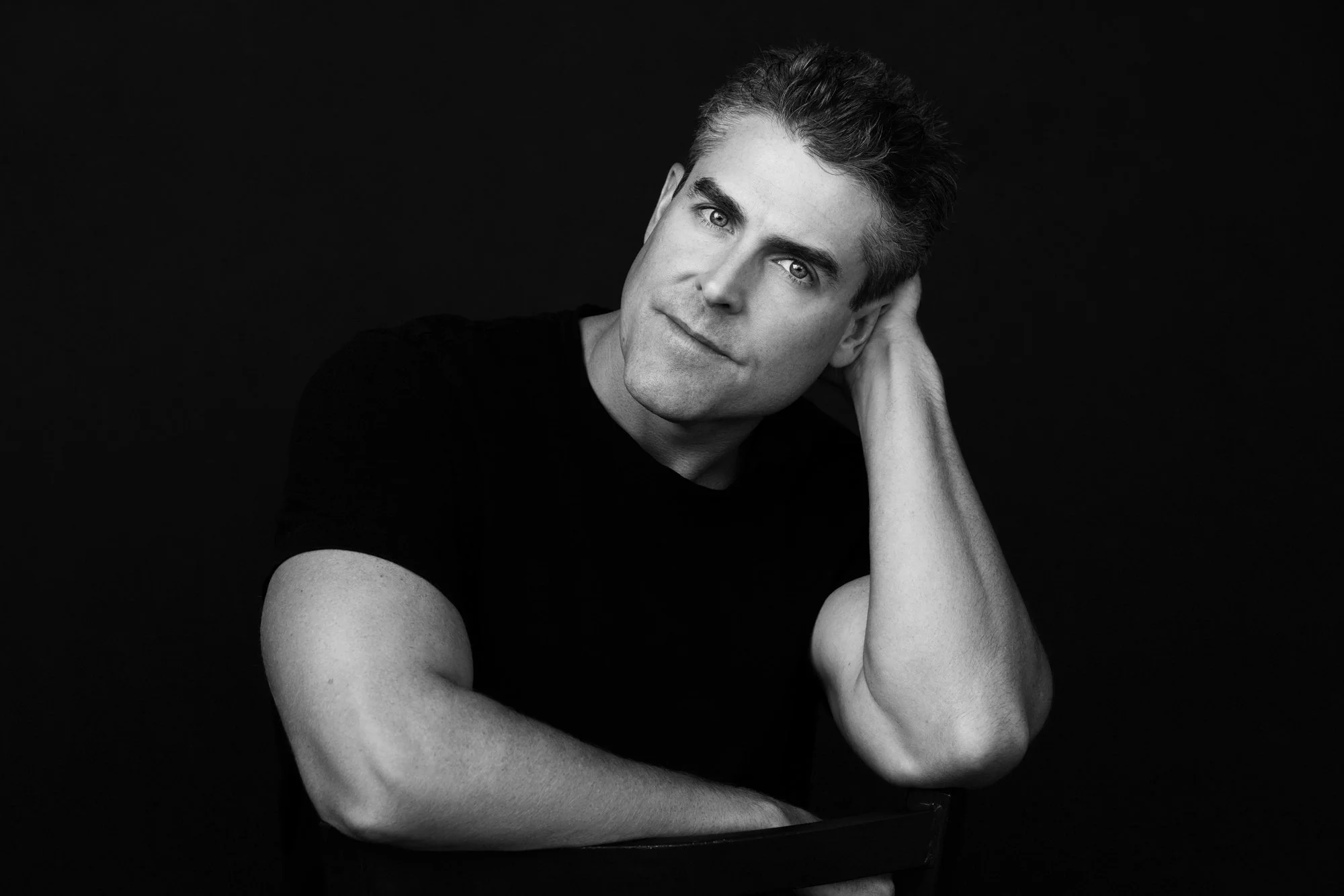 Black-and-white portrait of a man in a black t-shirt resting his head on his hand, Nashville men's portrait by Judith Hill