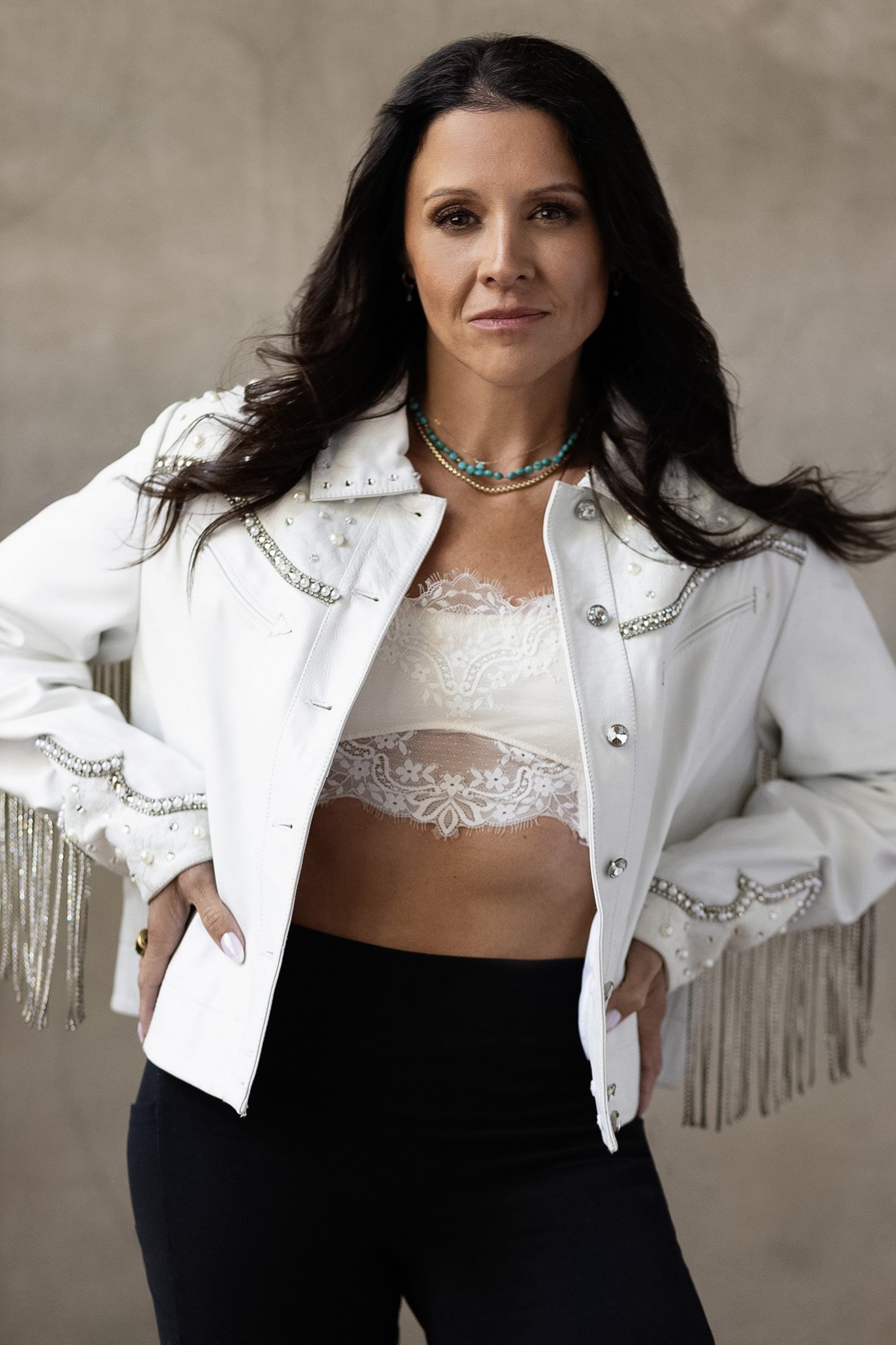 Brunette woman in a white western fringe jacket and turquoise necklace, Nashville style portrait by Judith Hill