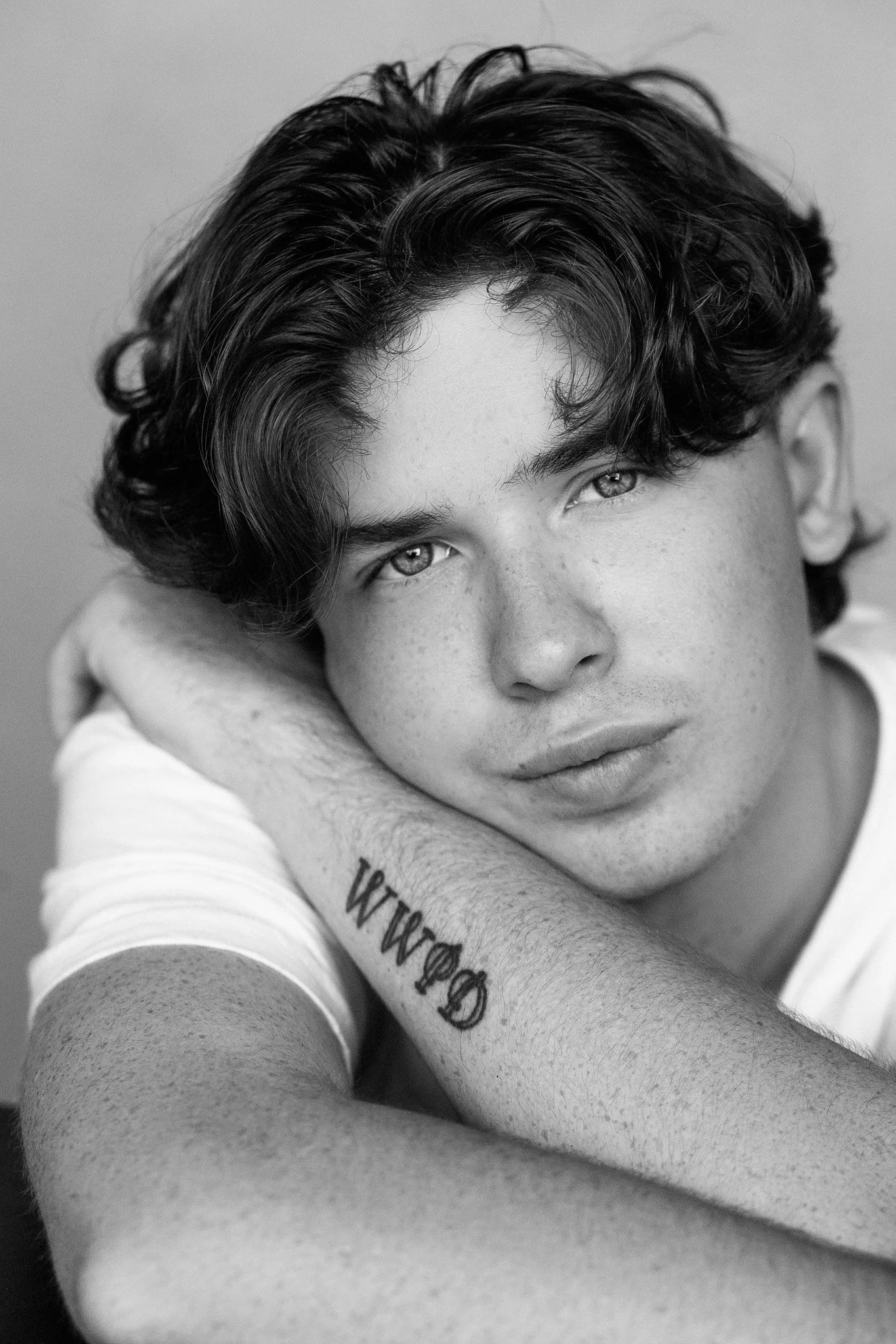Black-and-white portrait of a young man with curly hair and crossed arms, Nashville senior portrait by Judith Hill