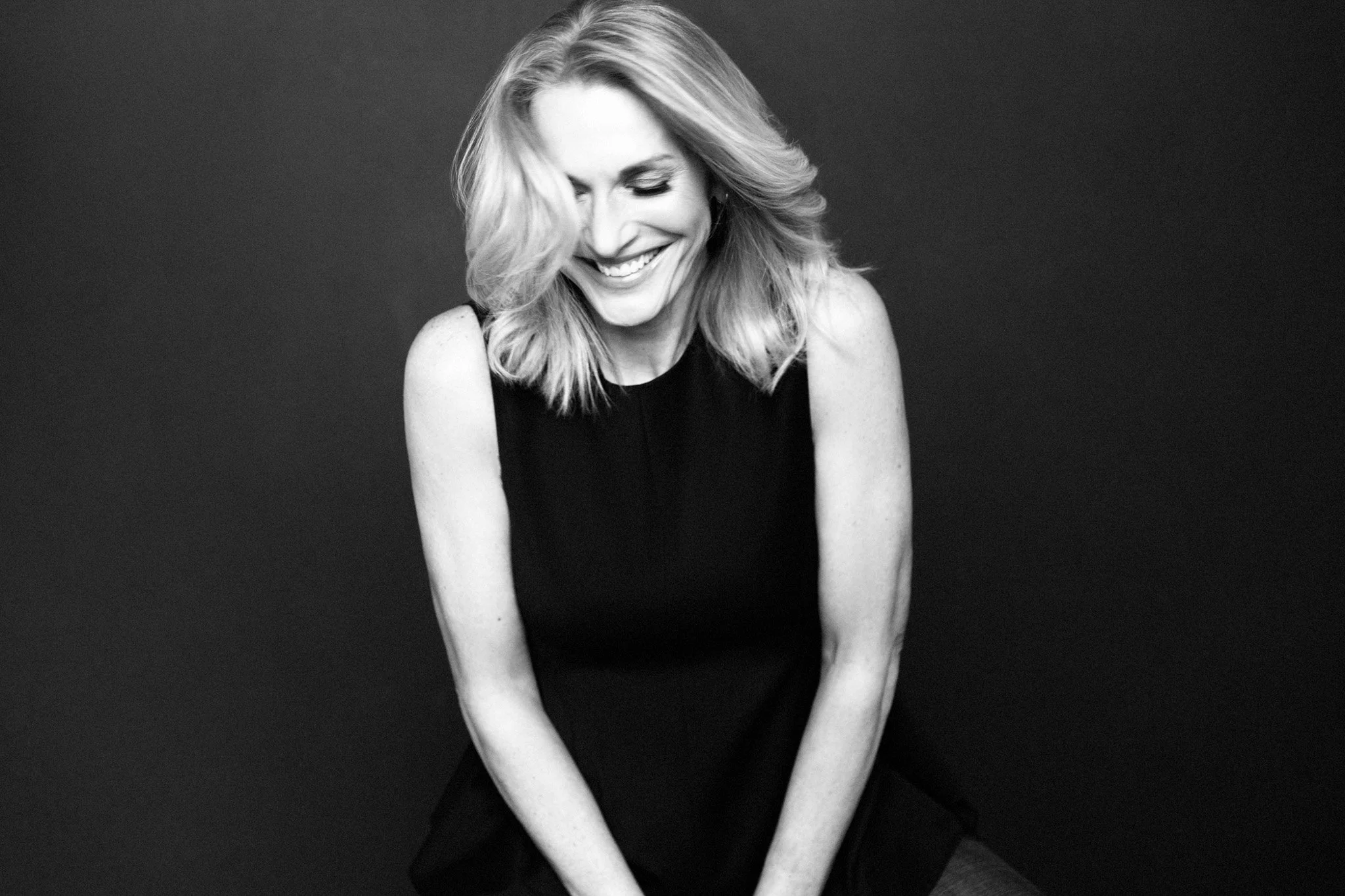 Black-and-white portrait of a blonde woman laughing in a black dress, Nashville studio portrait by Judith Hill