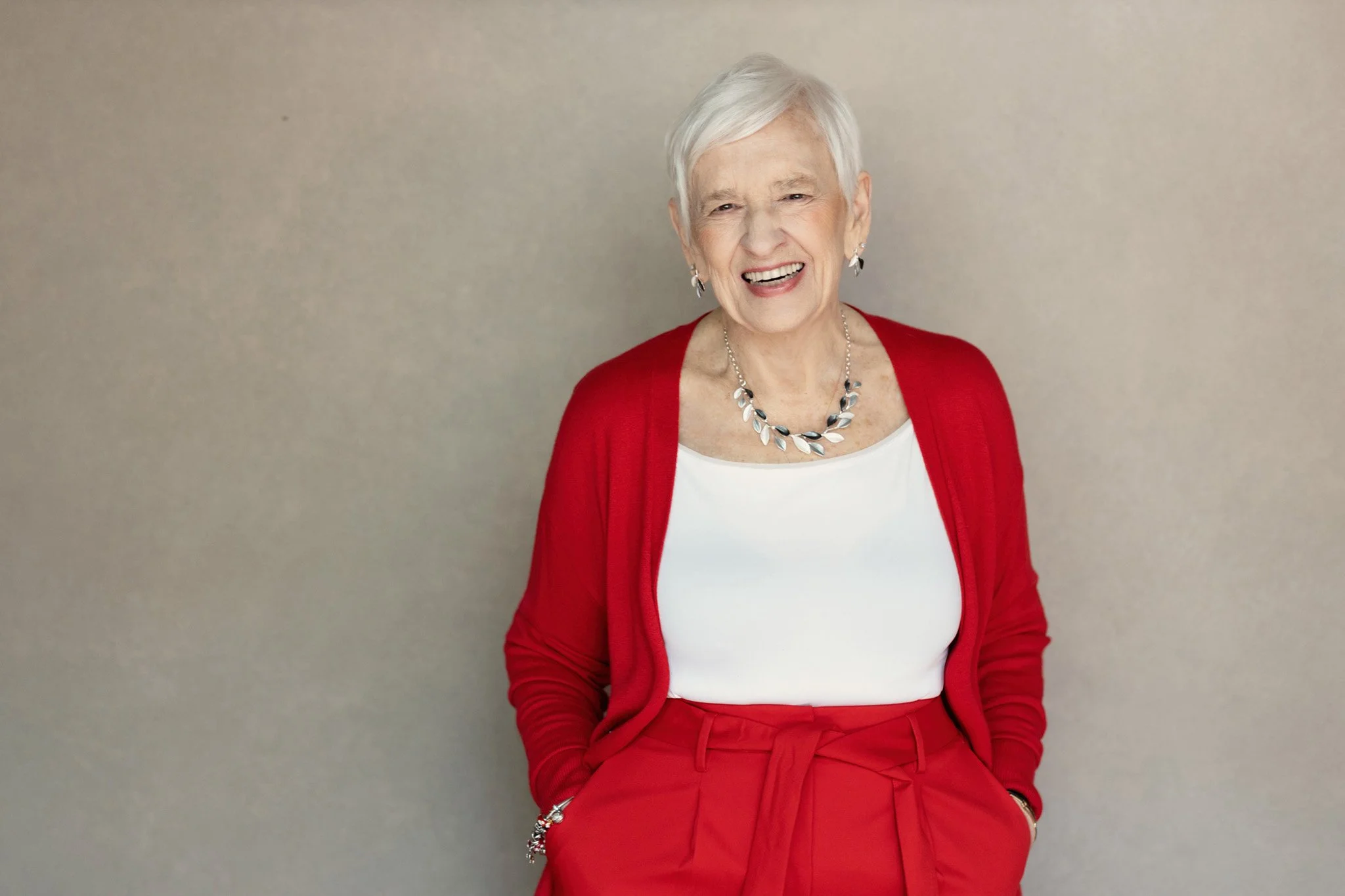 Joyful older woman laughing in a red cardigan, Nashville portrait by Judith Hill