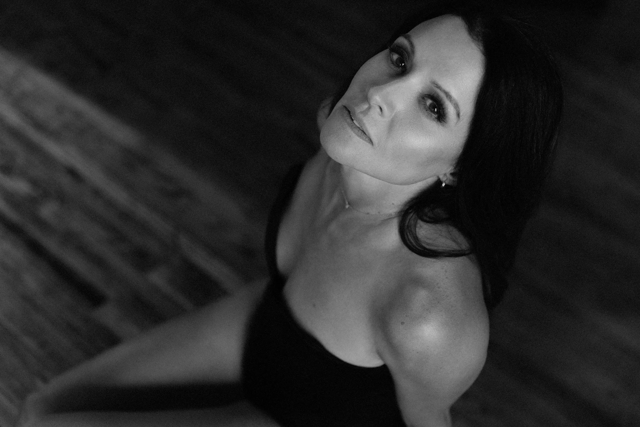 Brunette woman gazing up at the camera in a black top, dramatic overhead black and white — Nashville boudoir portrait