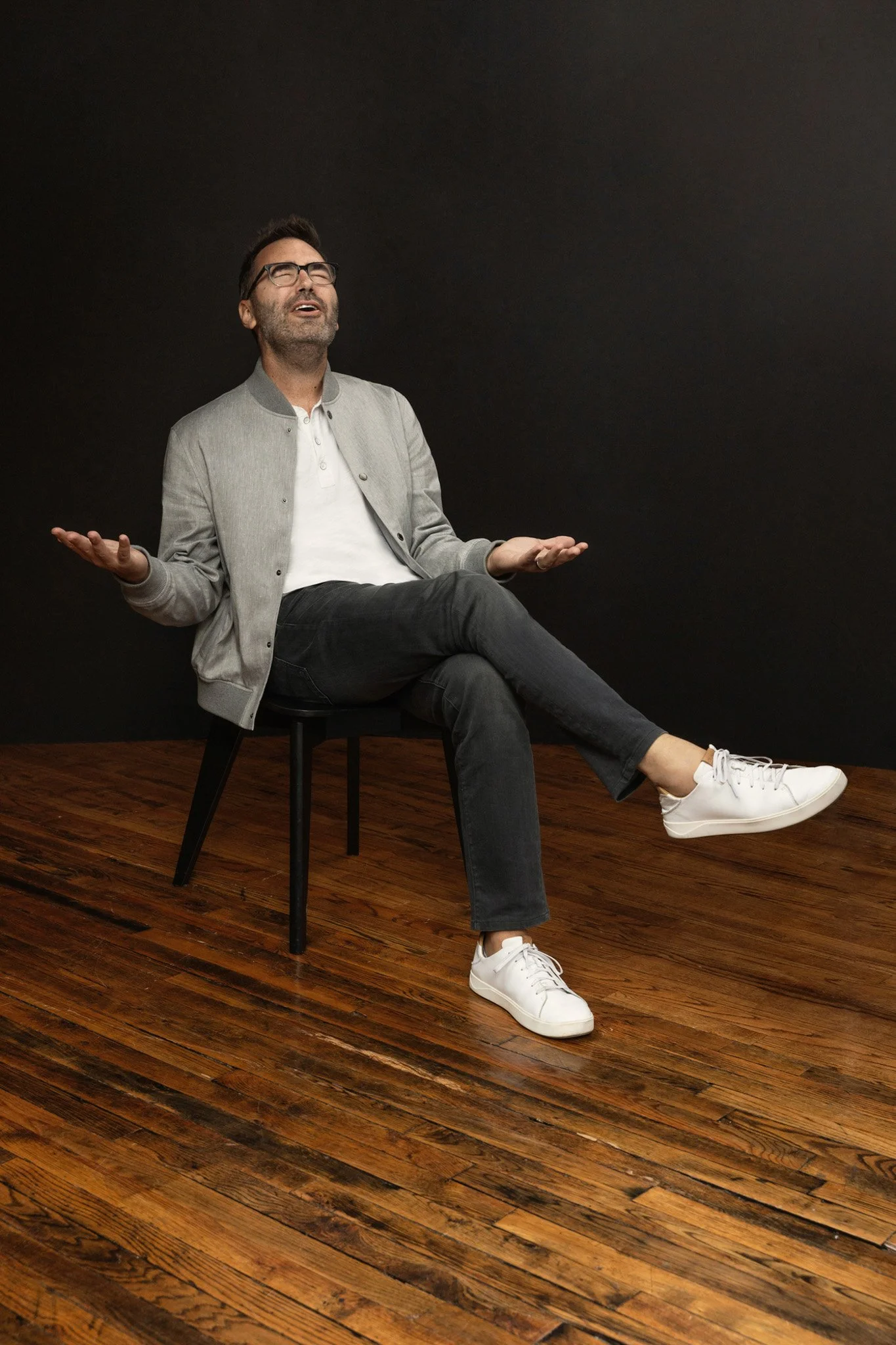 Man in a gray jacket and glasses laughing on a stool, Nashville personal-branding portrait by Judith Hill