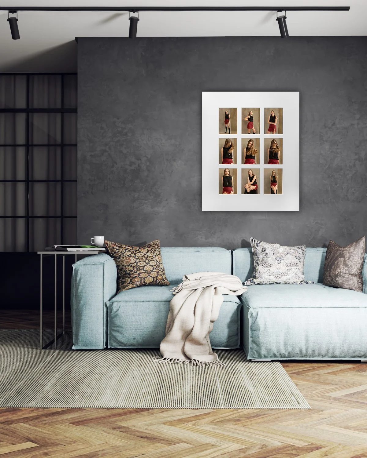 A contemporary living room mockup with a dark textured gray wall and a light blue fabric sectional sofa with throw pillows. Mounted on the wall is a large white multi-photo frame displaying a nine-image grid of a young woman in various poses.