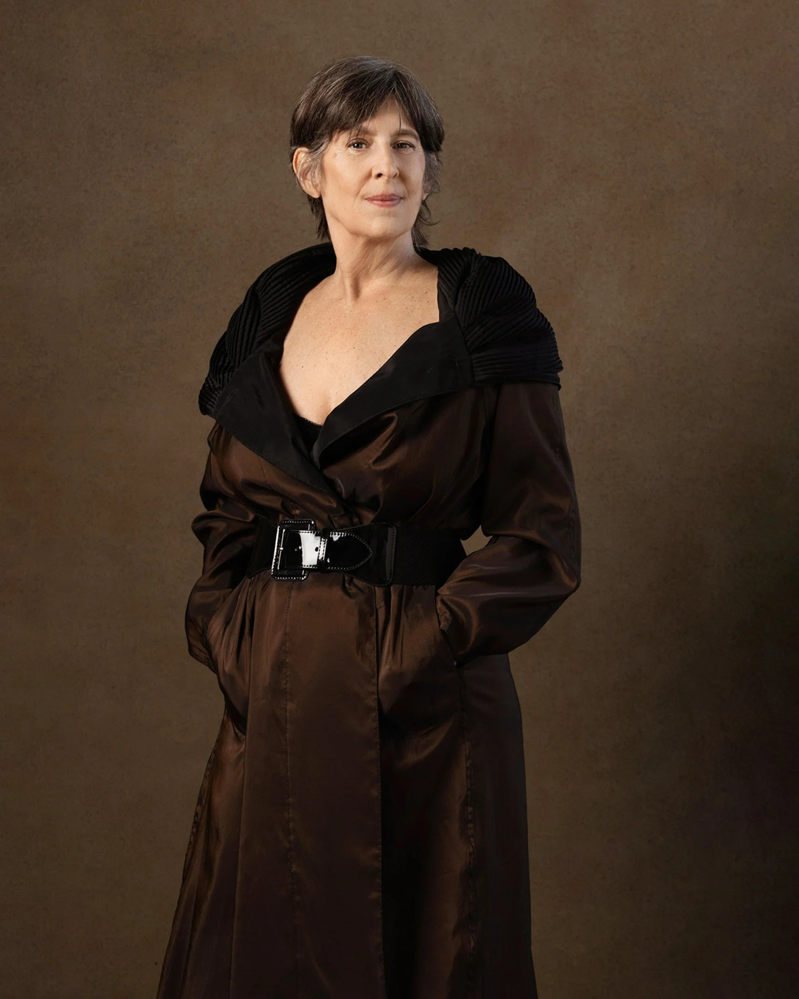 Older woman in a dramatic brown belted coat, Nashville character portrait by Judith Hill