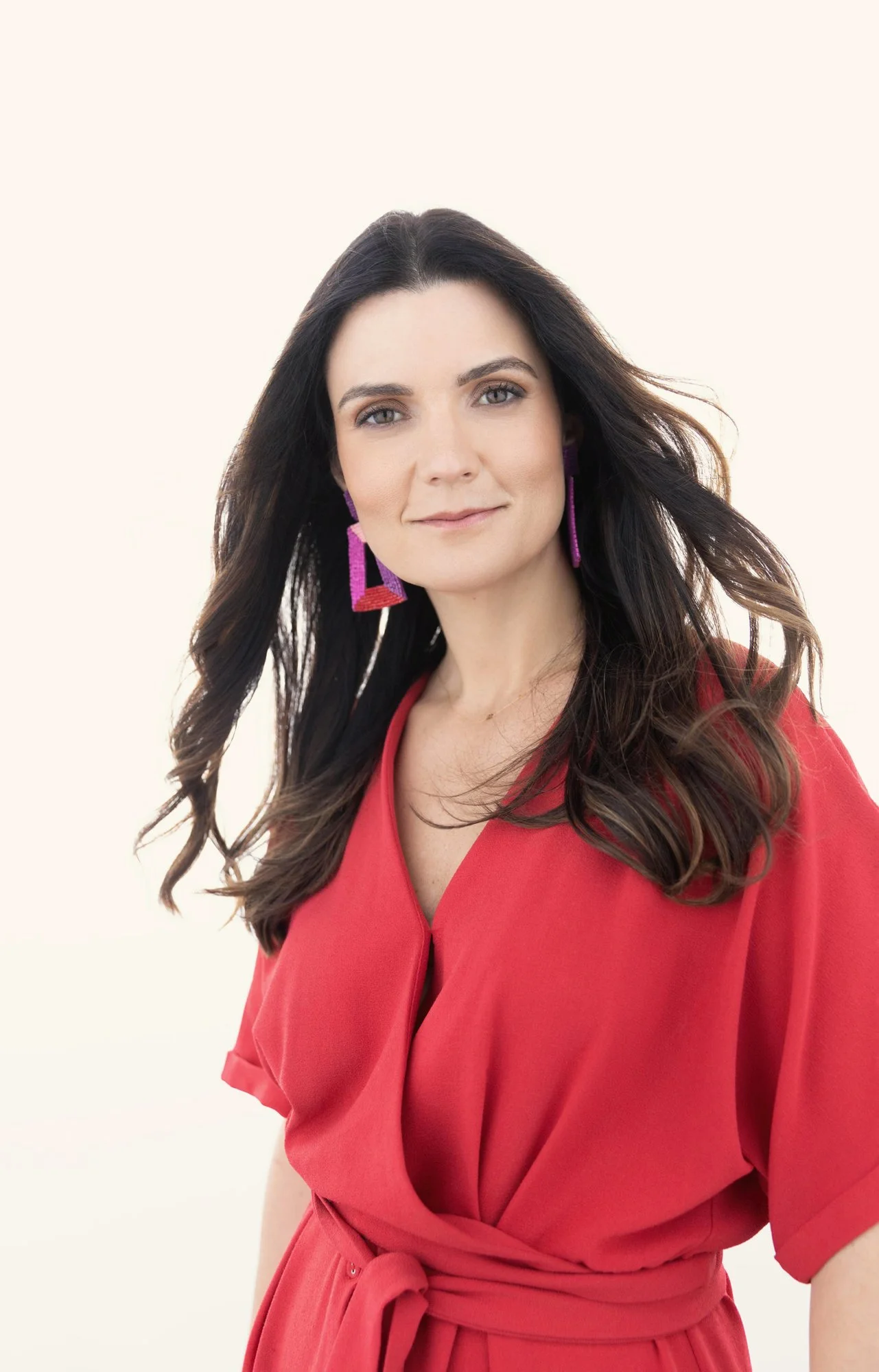 Brunette woman in a red wrap dress with statement earrings, Nashville studio portrait by Judith Hill