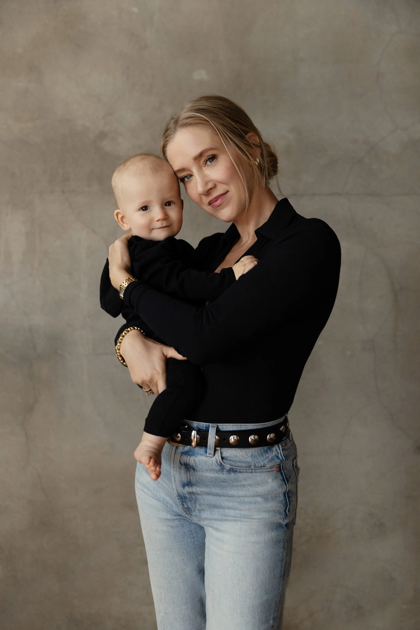 Mother holding her baby against a concrete wall, Nashville motherhood portrait by Judith Hill