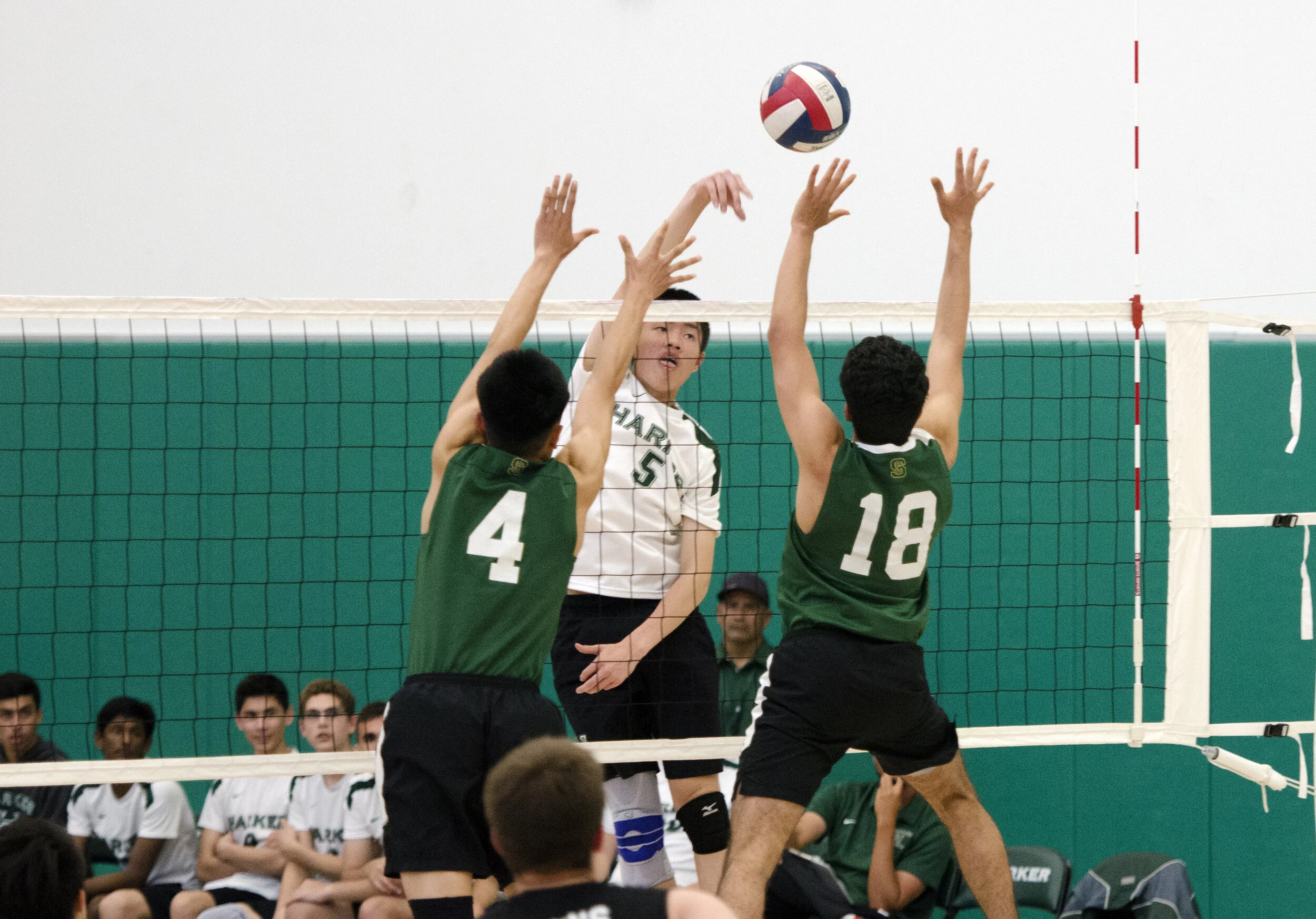 A Harker volleyball player spikes the ball above the hands of two blockers. Two freshmen played on the boys varsity volleyball team for the 2019 season. Photo by Eric Fang
