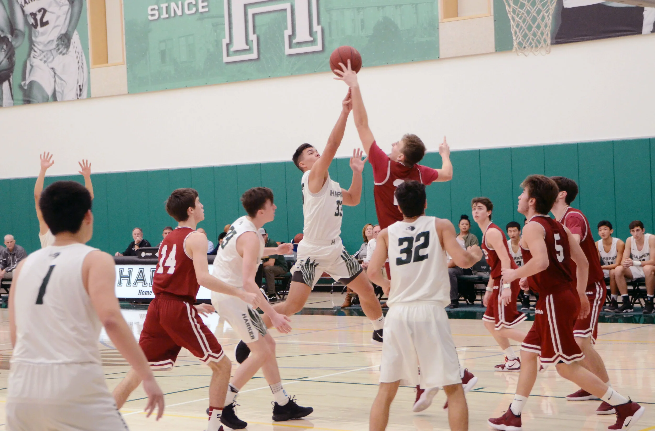 A Harker basketball player and a player from Sacred Heart both attempt to rebound a missed shot. A total of seven seniors currently play for the boys varsity basketball team. Photo by Eric Fang