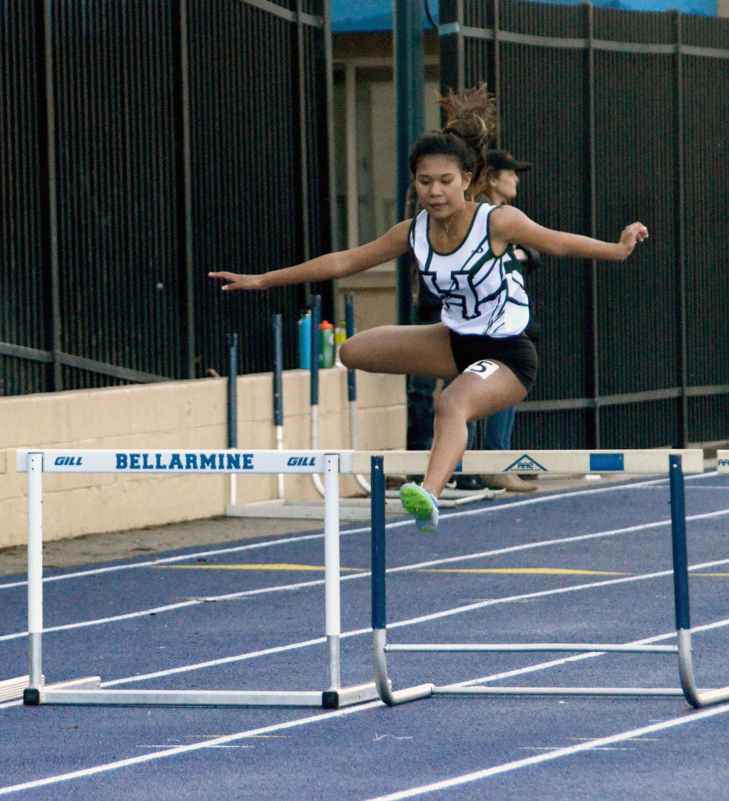 A Harker track and field runner jumps a hurdle at the Bellarmine High School Invitational Track Meet on Feb. 24, 2018. Harker’s head track and field coach retired after the 2018 season. Photo by Eric Fang