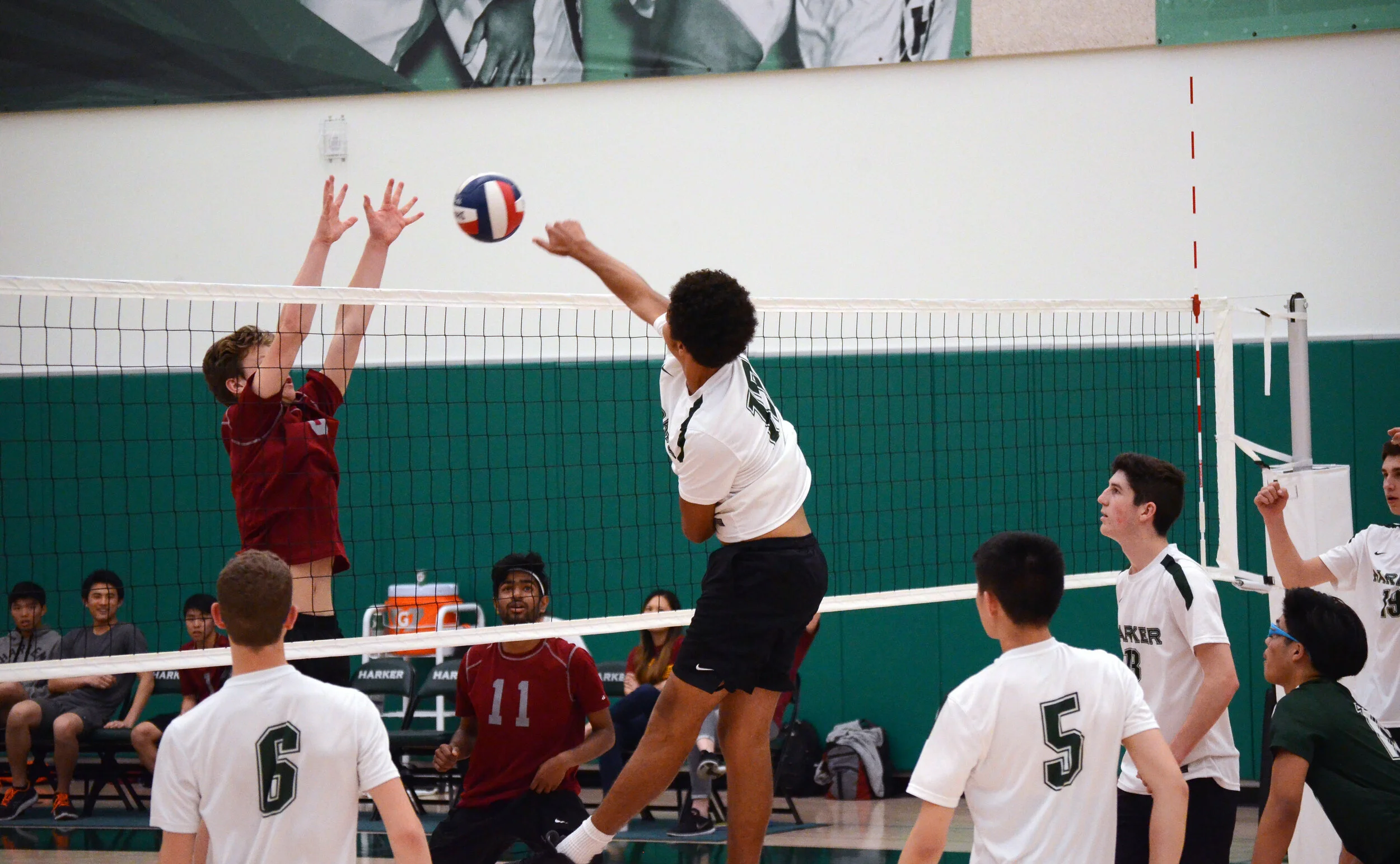 A Harker volleyball player spikes the volleyball between two opposing blockers in a NorCal Division III playoffs match against St. Vincent High School on May 23, 2018. The Harker volleyball team made it to the semifinals of the NorCal Championships.…