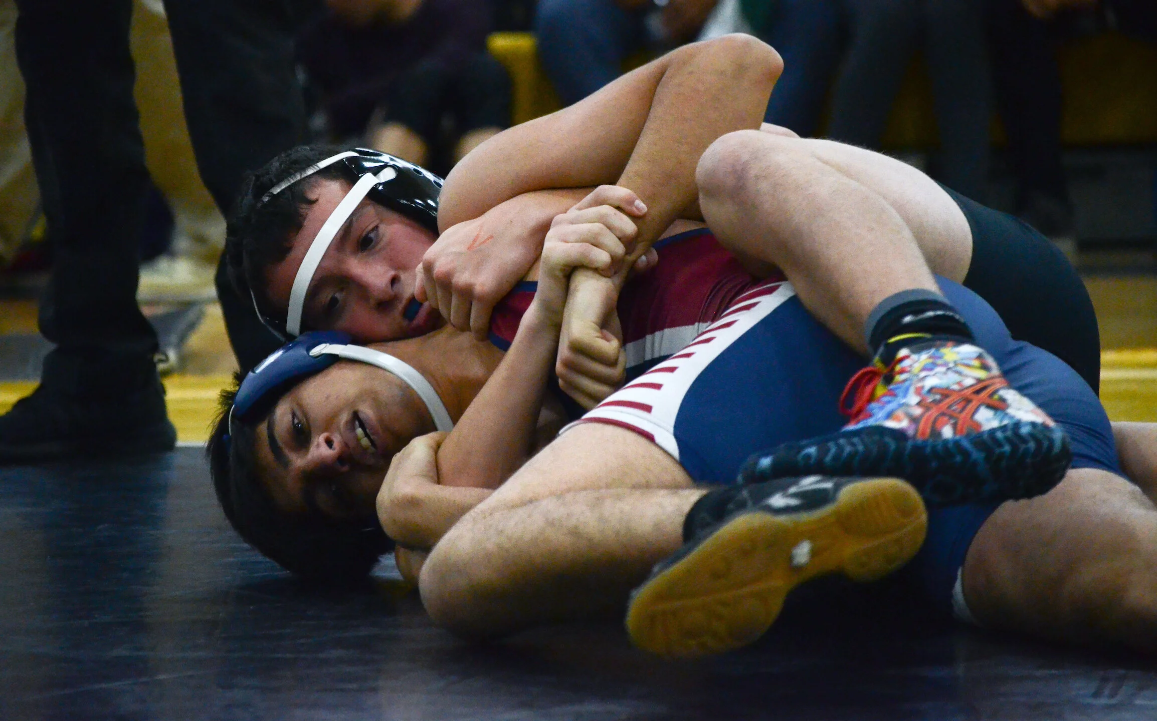 A Harker wrestler wraps his leg over his opponent, pinning him to the ground at a January 27, 2018 tournament at Del Mar High School. The Harker wrestler placed second in his 127 lb. weight class. Photo by Eric Fang