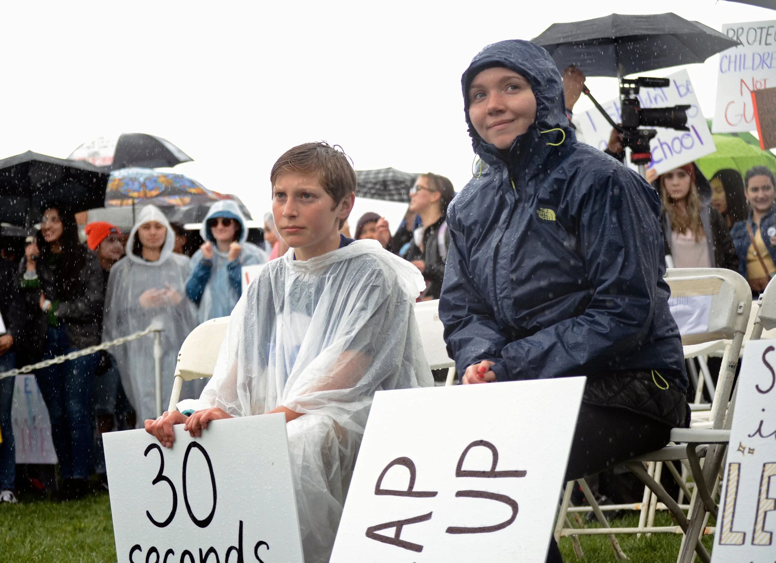 A mother listens to speeches at the March for Our Lives rally in San Jose with her son. Protesters marched down Santa Clara Street in downtown San Jose before holding a rally at Arena Green. Photo by Eric Fang