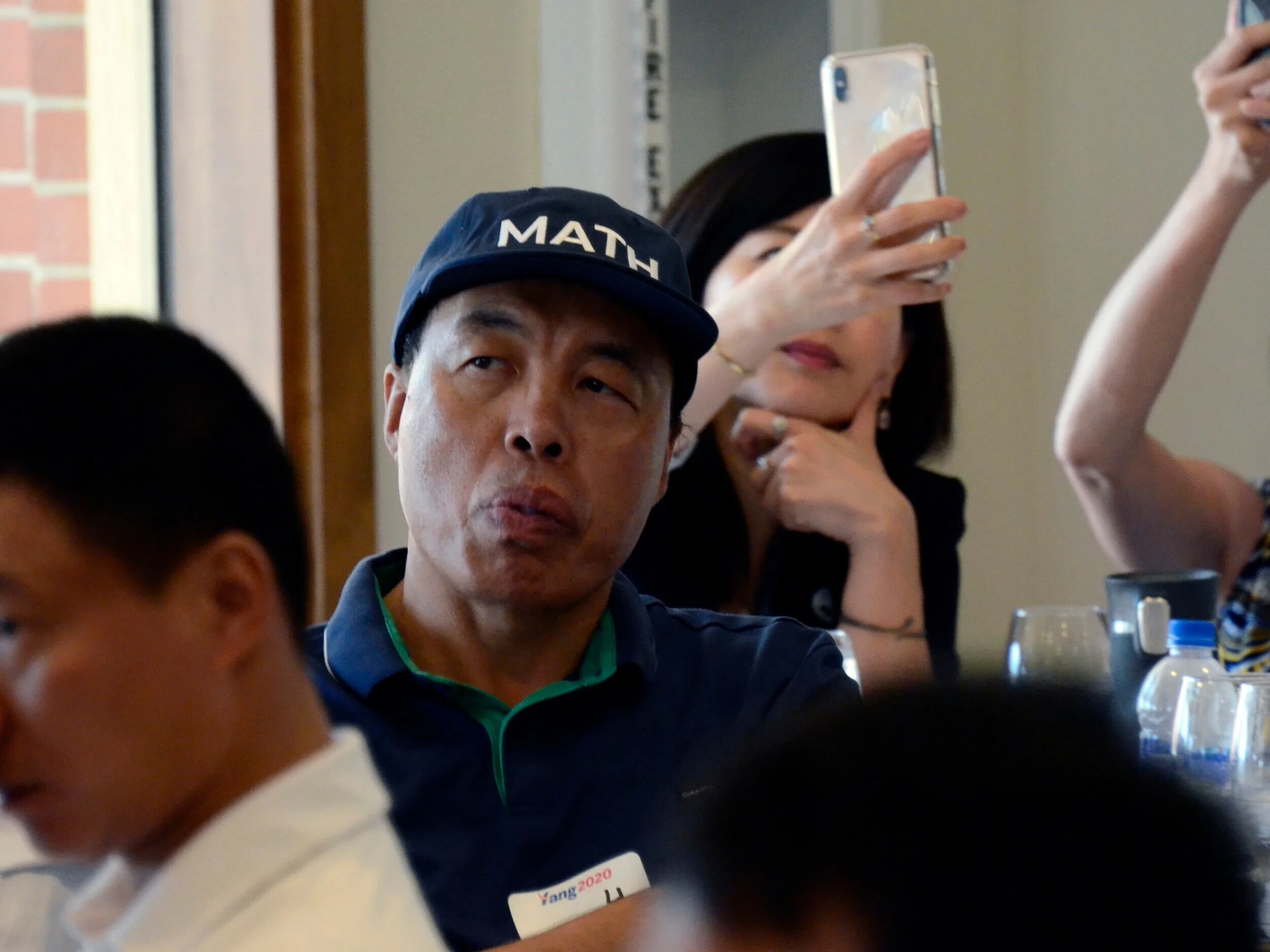 An Andrew Yang supporter wearing a “MATH” hat listens to Yang speak about increasing automation and the changing nature of the U.S. economy. In Yang’s campaign, “MATH” stands for “Make America Think Harder.” Photo by Eric Fang