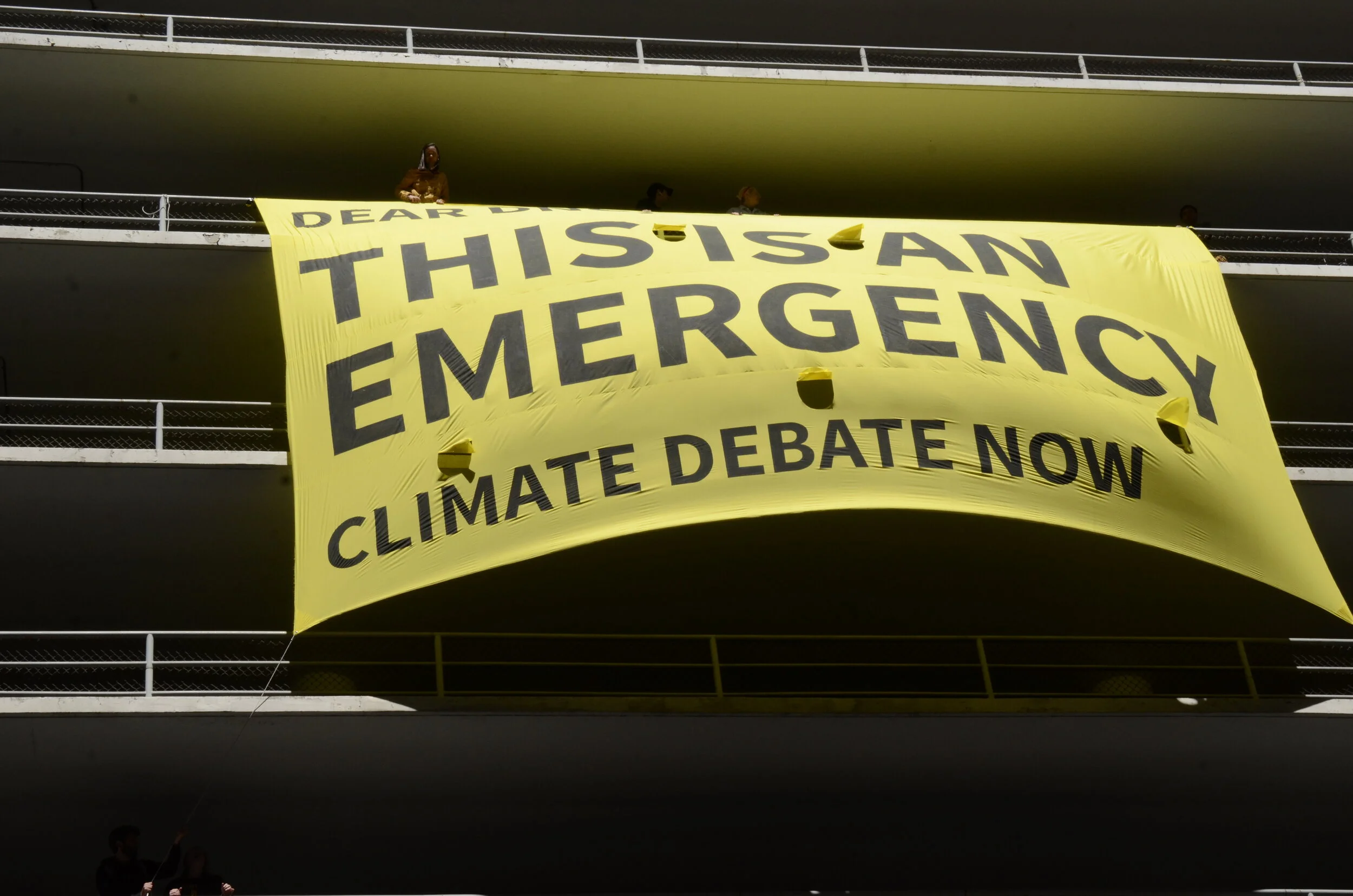 Sunrise Movement protesters displayed a large banner on the parking structure across from the Hilton hotel where the Democratic National Committee summer meeting was taking place. Governor of Washington Jay Inslee threw his support behind a climate …