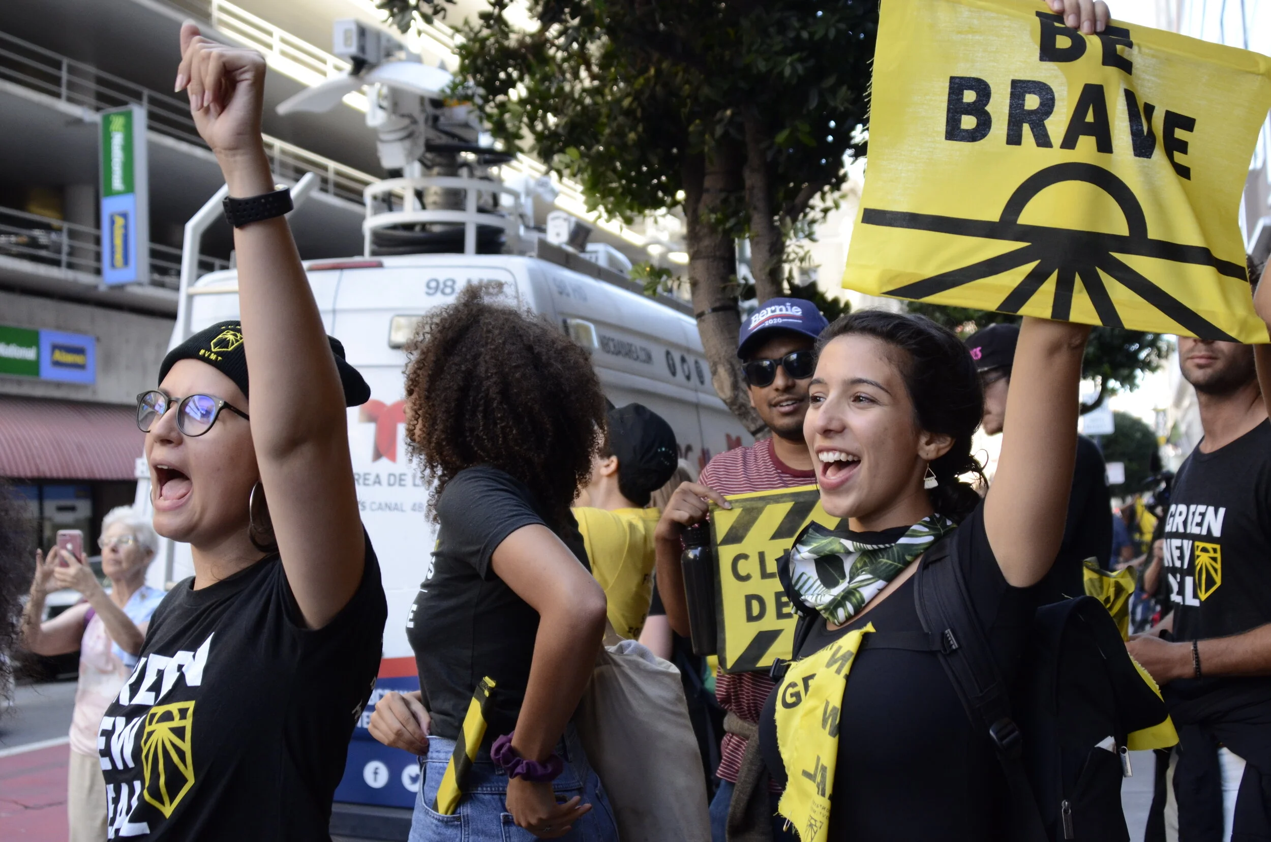A protester from the Sunrise Movement holds up a bright yellow sign bearing the words “Be Brave” outside the Hilton San Francisco Union Square hotel. The protesters called on Democratic National Committee (DNC) members to allow for a Democratic pres…