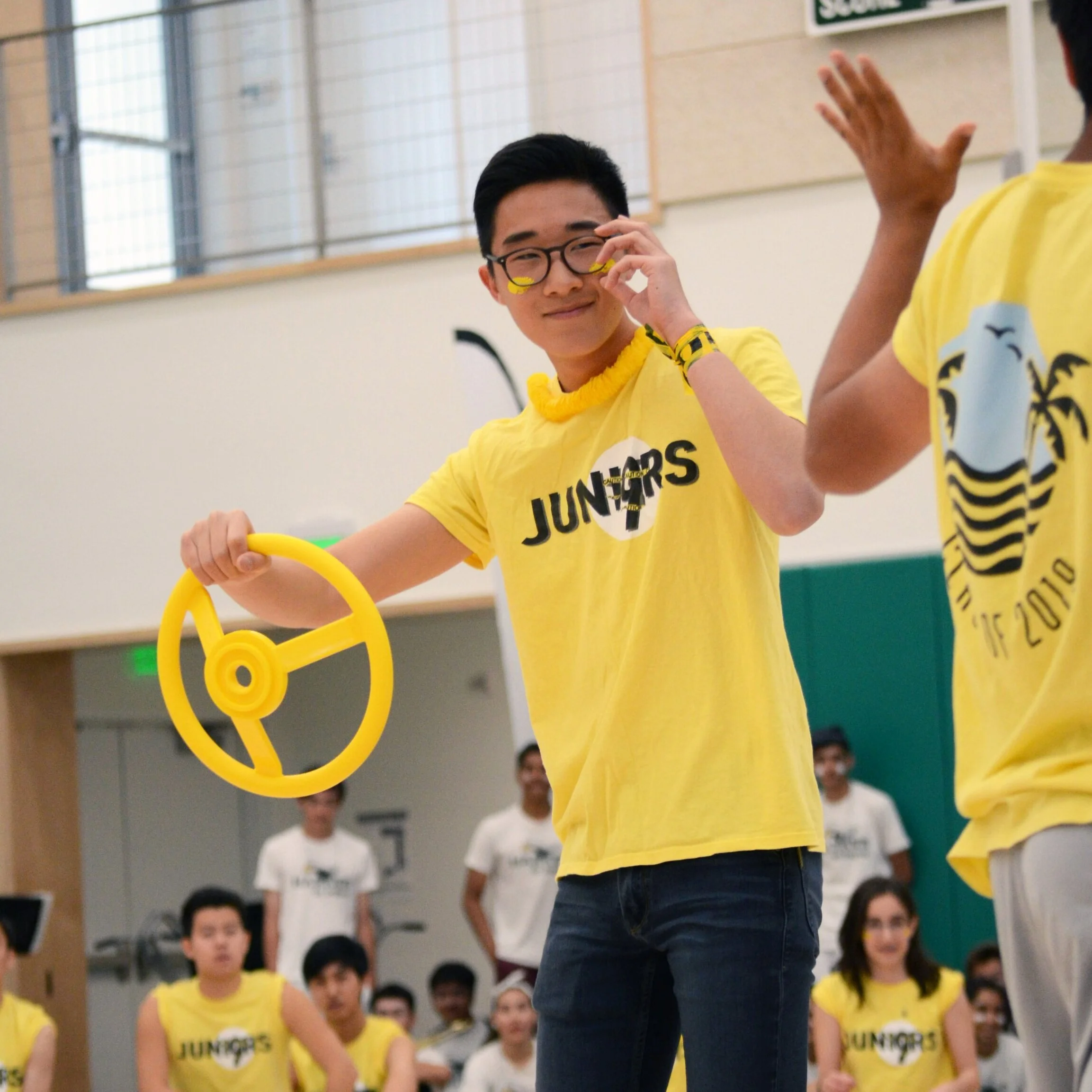 A junior smiles as he holds a steering wheel, a prop in the class’s spring rally skit. The juniors performed the skit as the song “Tokyo Drift” by Teriyaki Boyz played in the background. Photo by Eric Fang