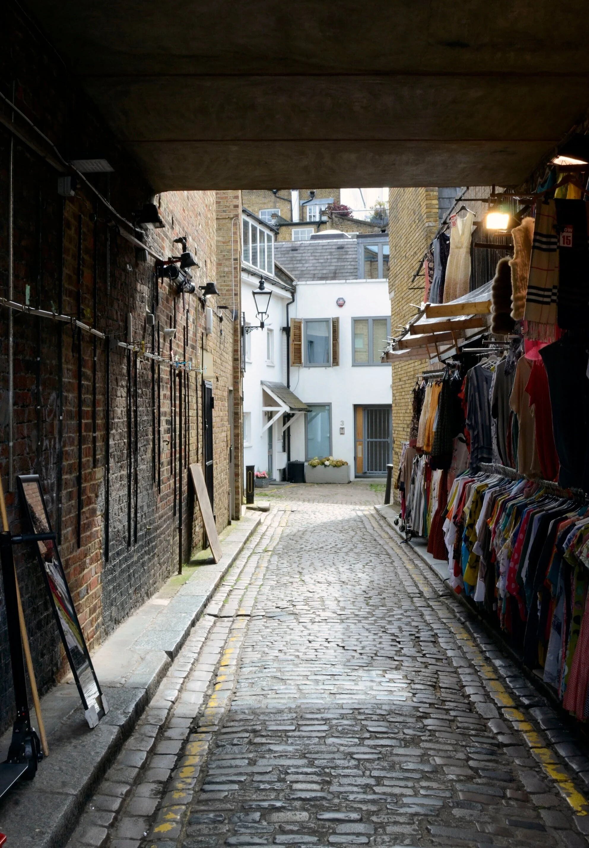A street vendor displays a colorful array of clothes in an alley close to Portobello Road in London on June 12, 2019. Portobello Road boasts the world's largest antiques market with over 1,000 dealers selling every kind of antique and collectible. P…