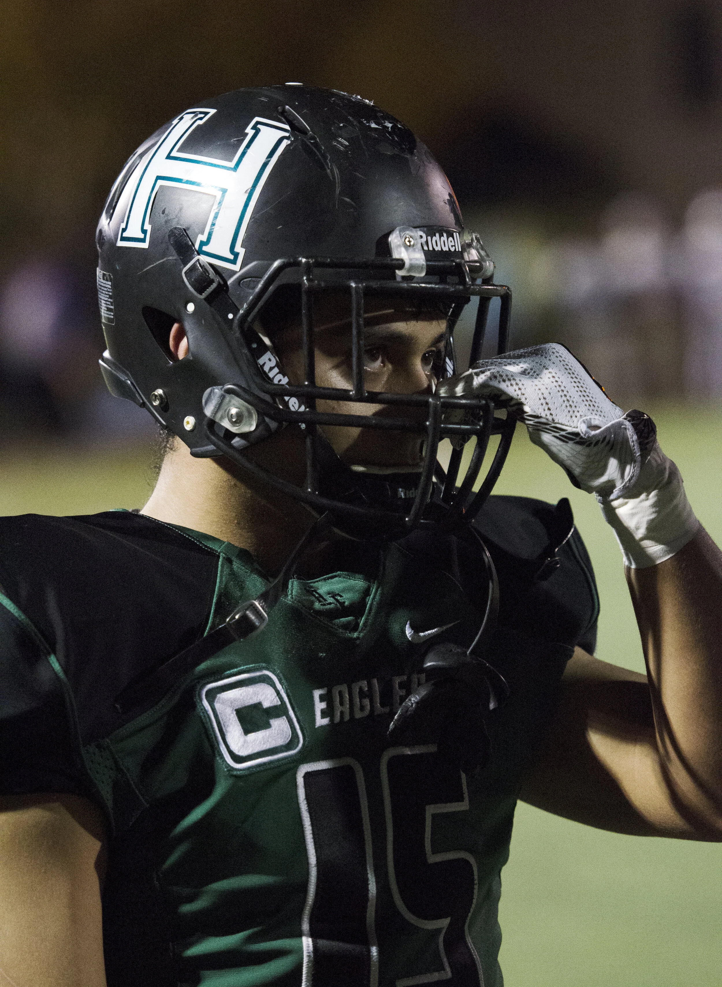 A Harker safety looks through his helmet visor on the sidelines as his teammates compete on the field. The varsity football team had 18 seniors during their 2017-2018 season. Photo by Eric Fang