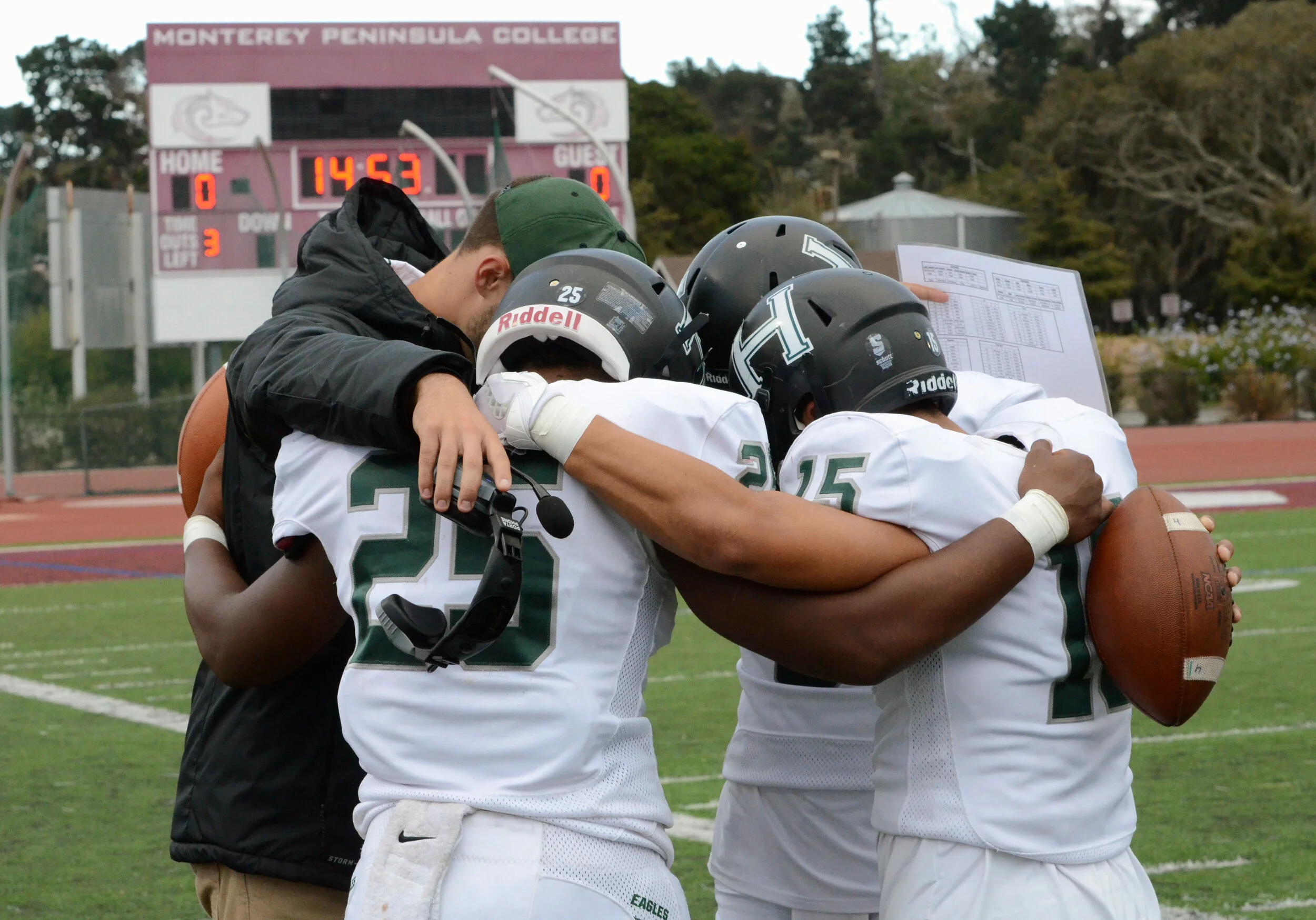 A Harker varsity football coach huddles with his team captains before a game against Marina High School on Nov. 25, 2017. The varsity football team has five coaches. Photo by Eric Fang