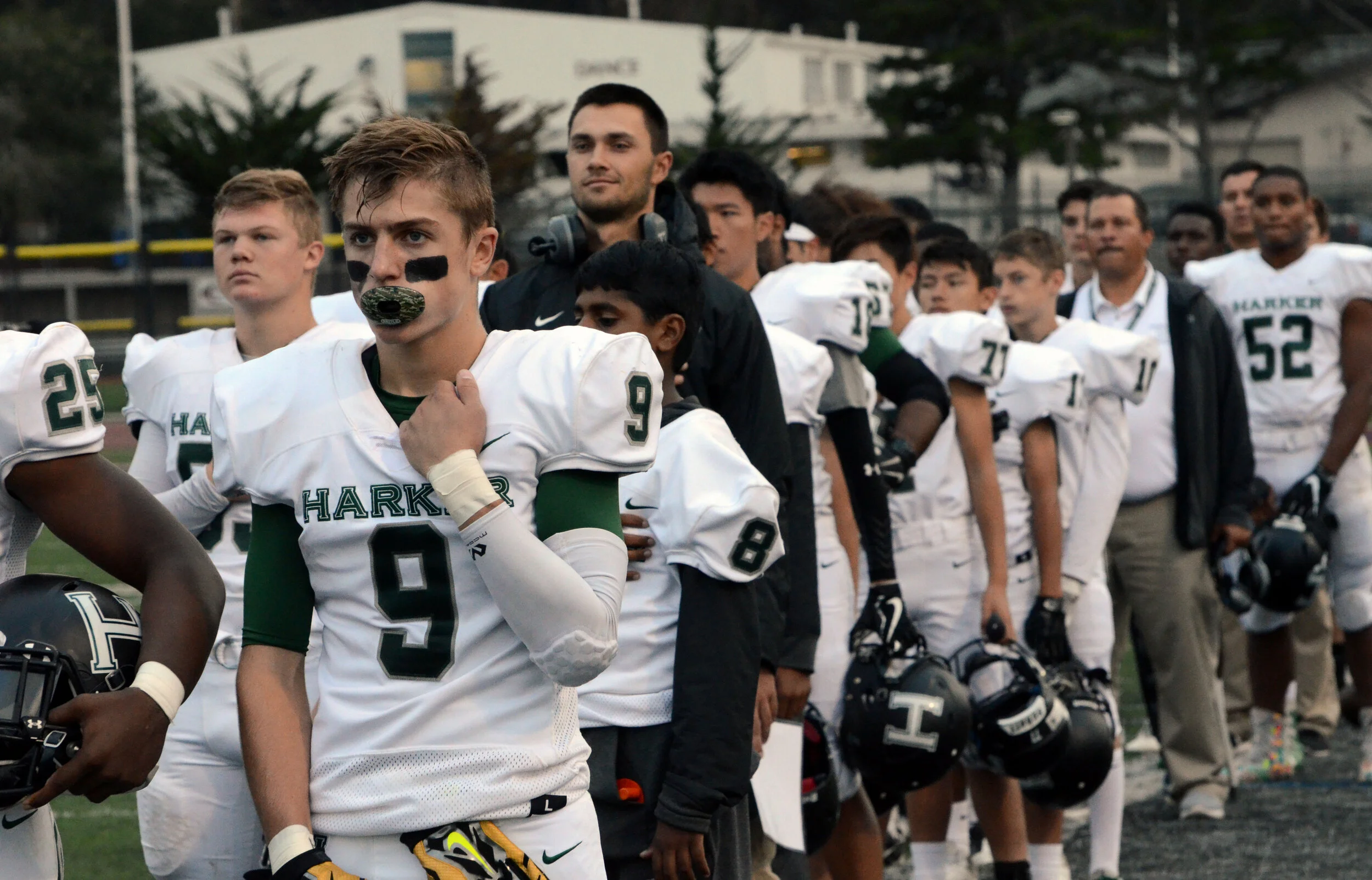 Football players from the Harker School’s varsity team stand in silence as the national anthem plays before their game on September 29, 2017. The team went undefeated until their last game against Hercules High School on Nov. 25, 2017. Photo by Eric…