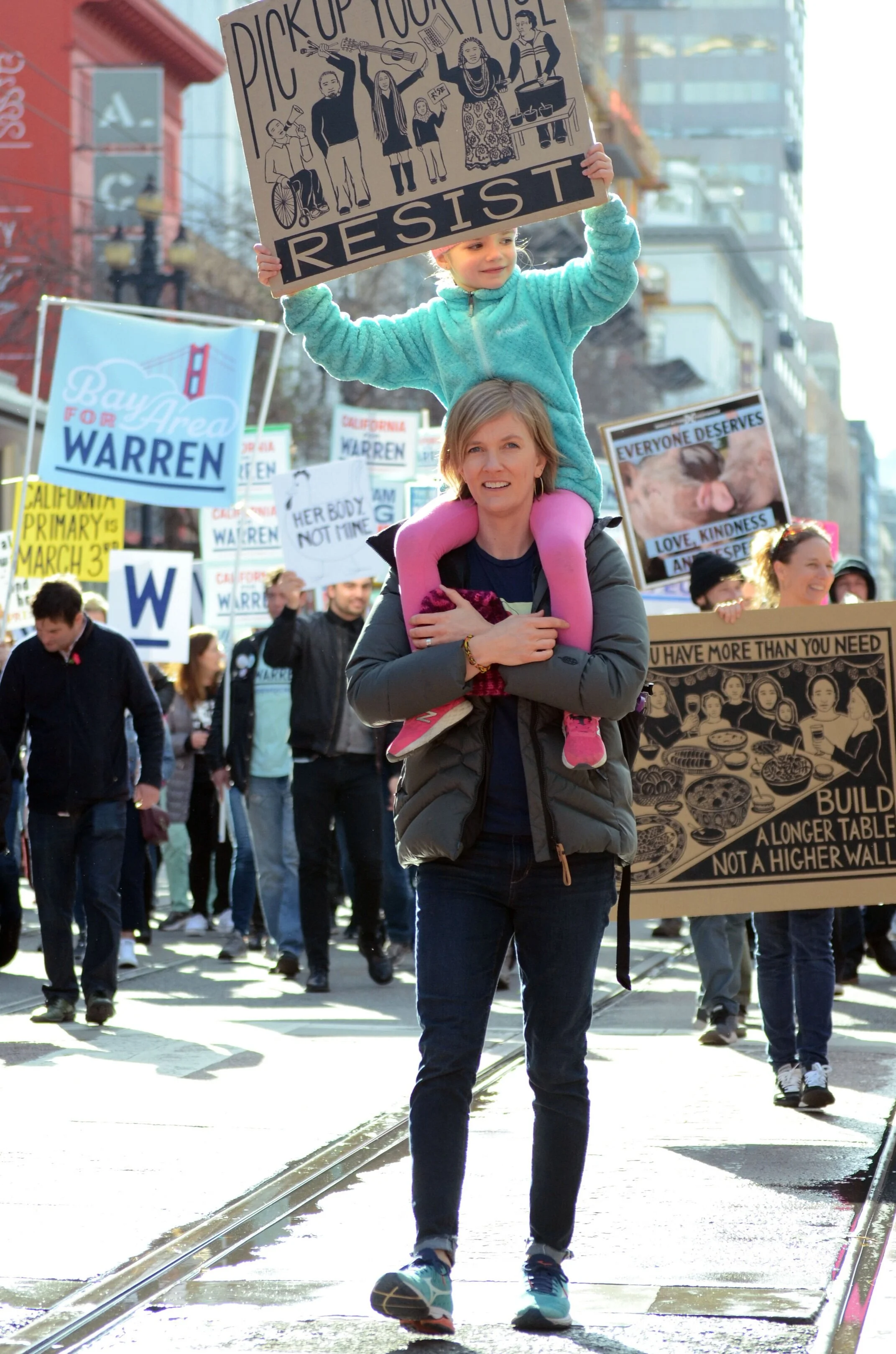 A mother carries her daughter on her shoulder as they march towards the Embarcadero. San Francisco Mayor London Breed addressed the crowd of thousands in a rally before the march. Photo by Eric Fang