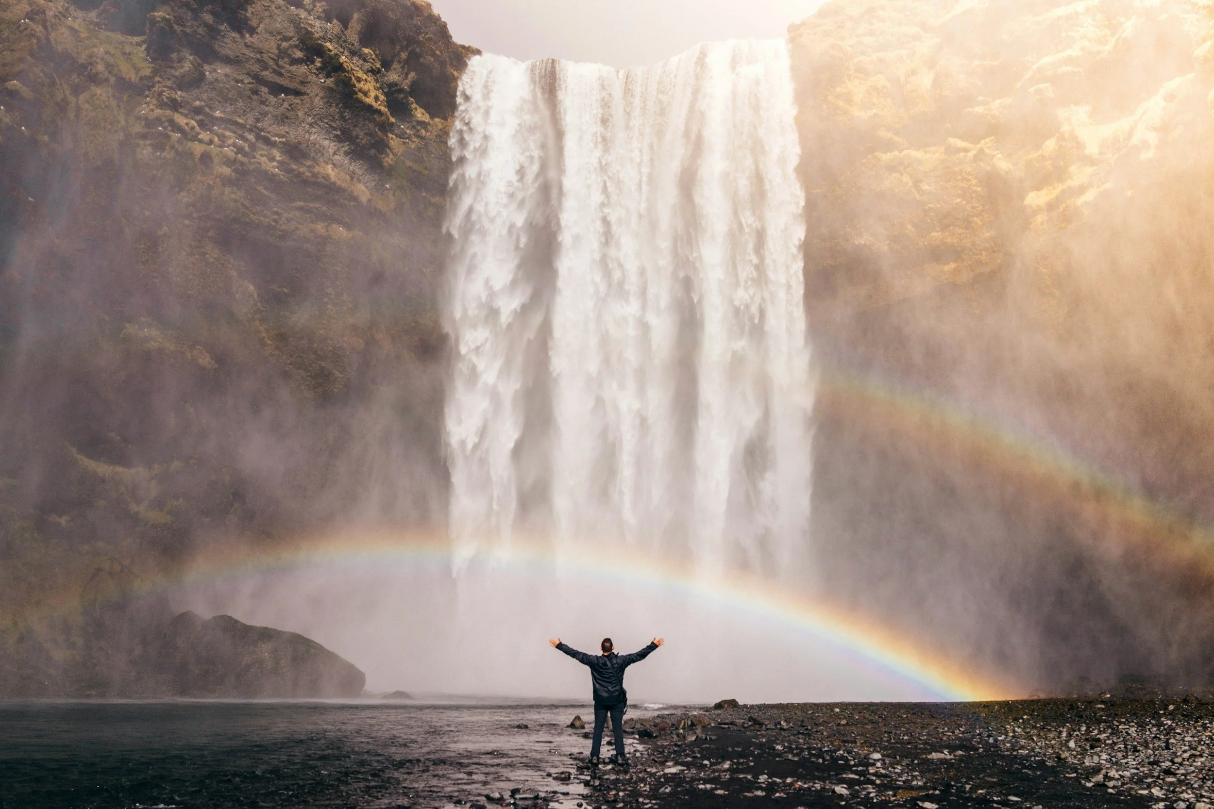ocean with rainbow and rock bridge