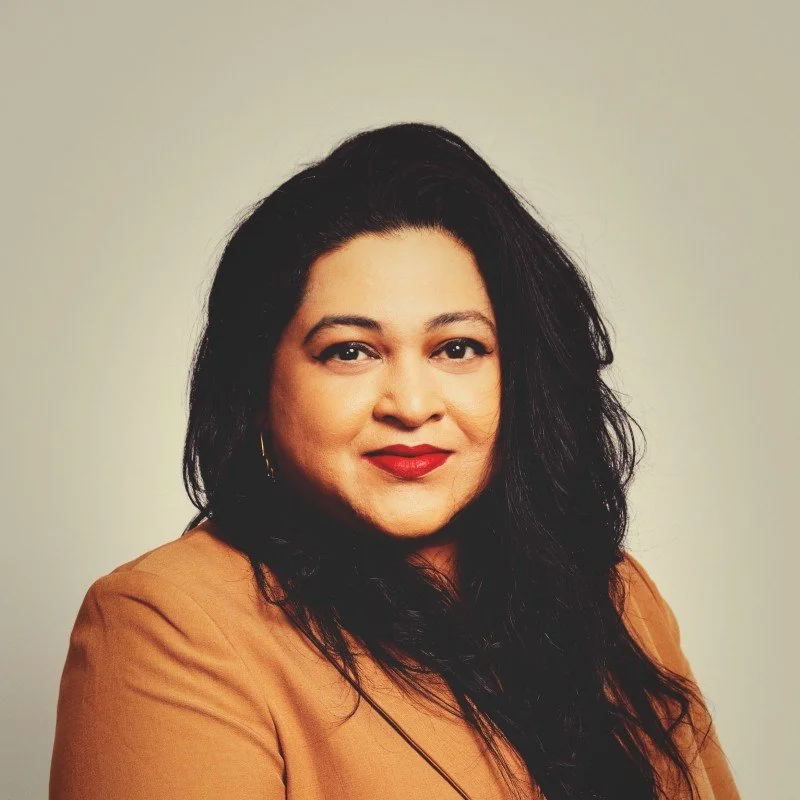 headshot of woman with brown hair and umber jacket