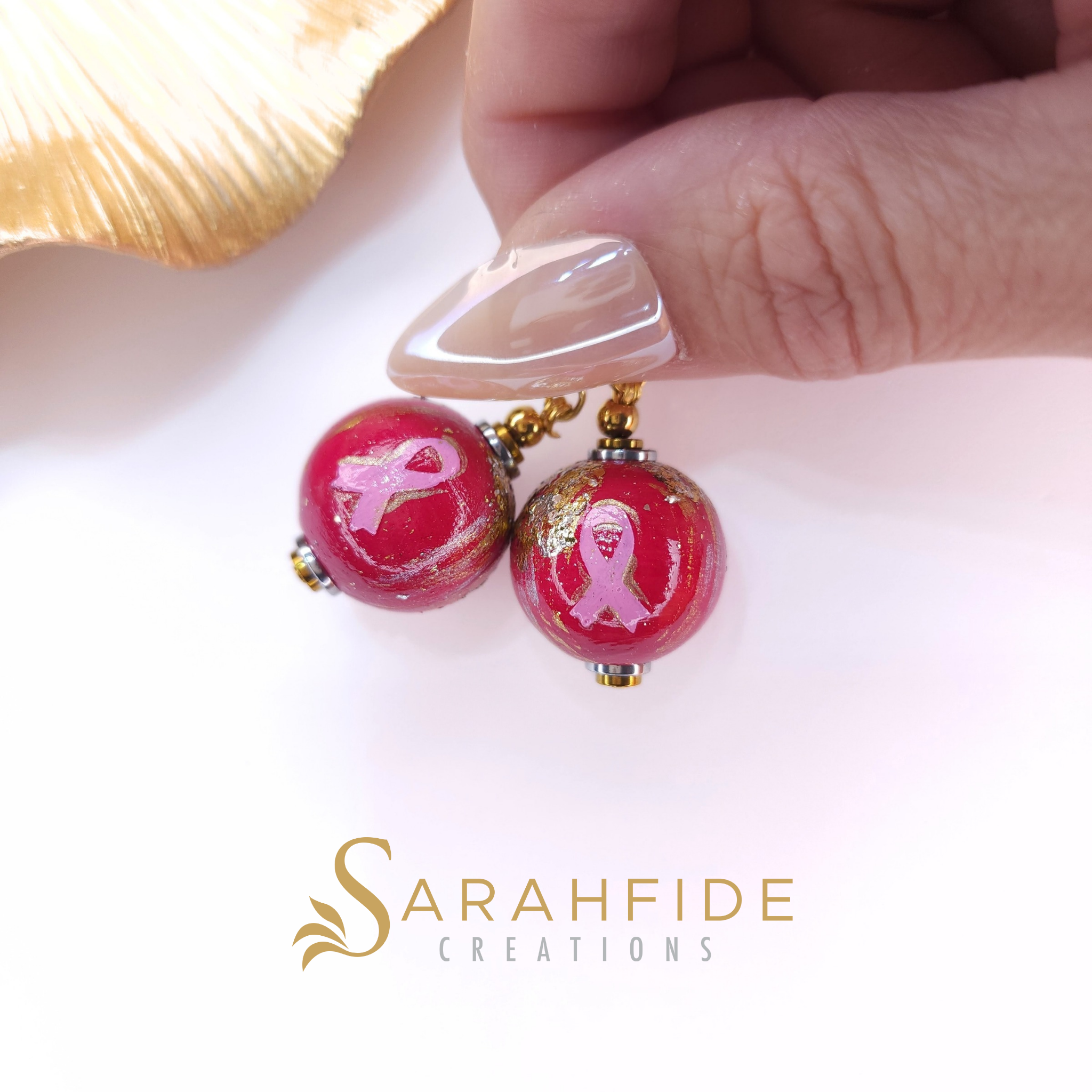 Breast Cancer Awareness Bougie Shy Dangle Earrings held in hand, pink ribbon beads