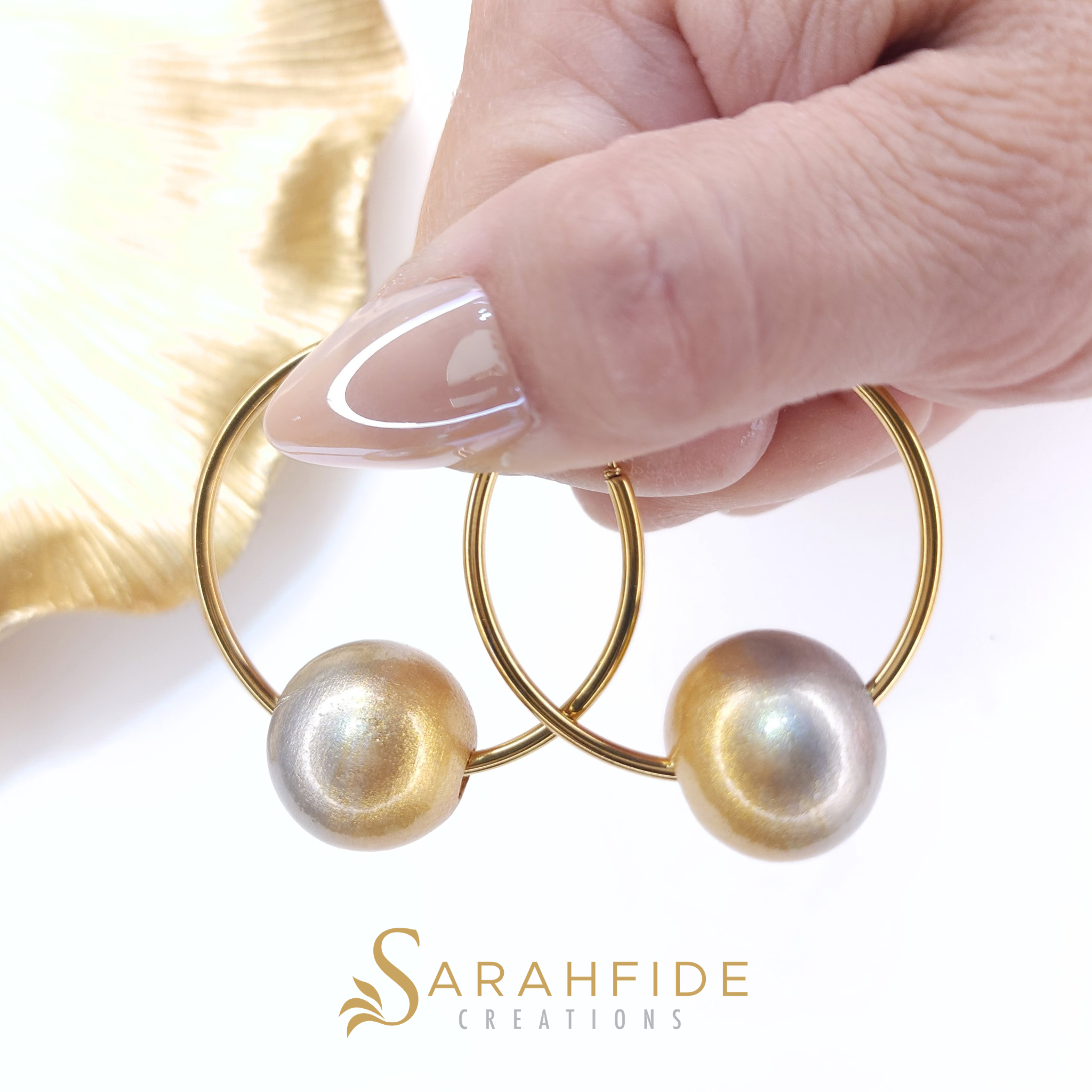 Platinum Bougie Hoop Earrings with gold hoops, held in hand