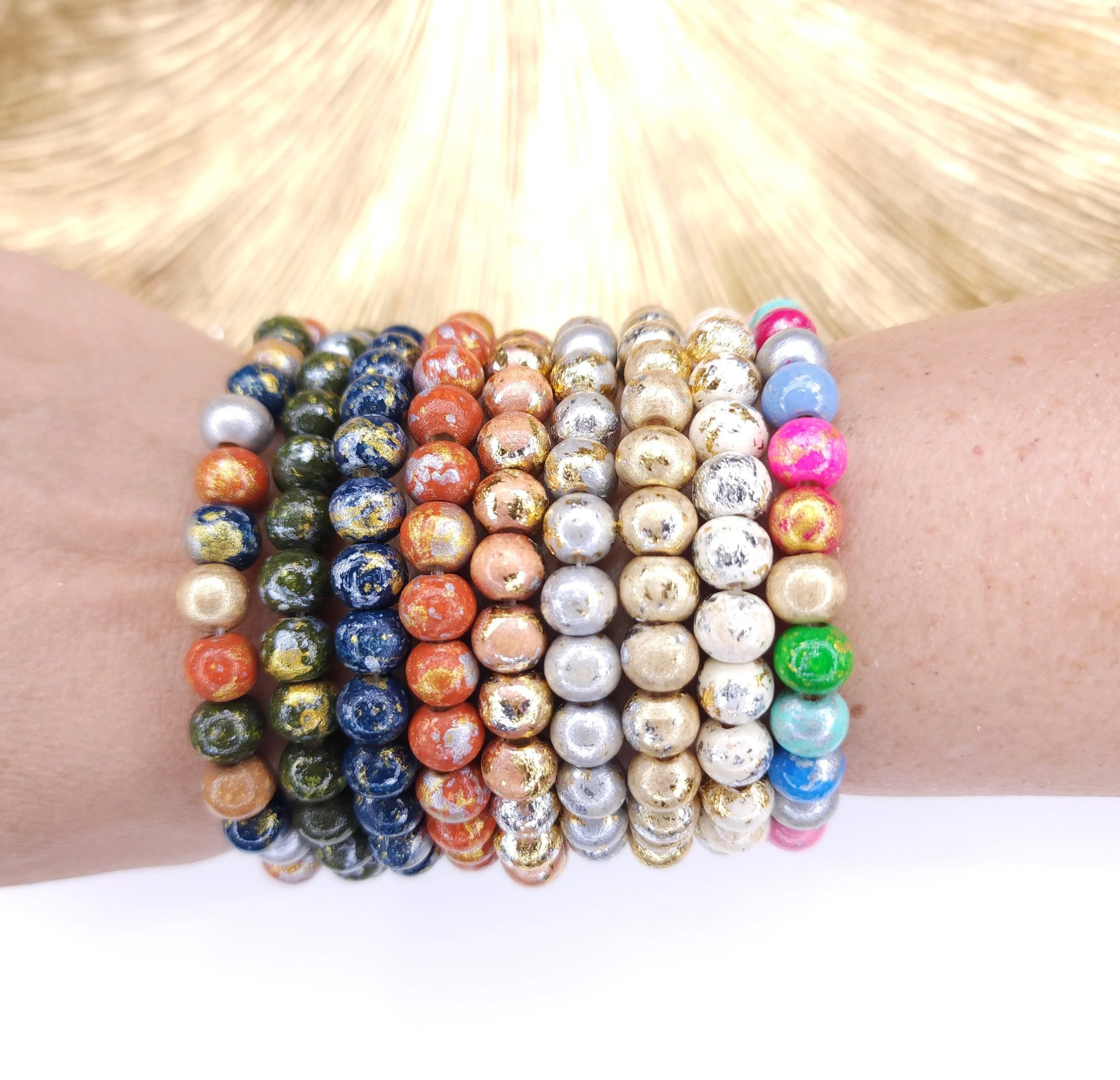 Stack of hand-painted wood bead stretch bracelets in navy, green, orange, gold, silver and pink with gold and silver sparkle