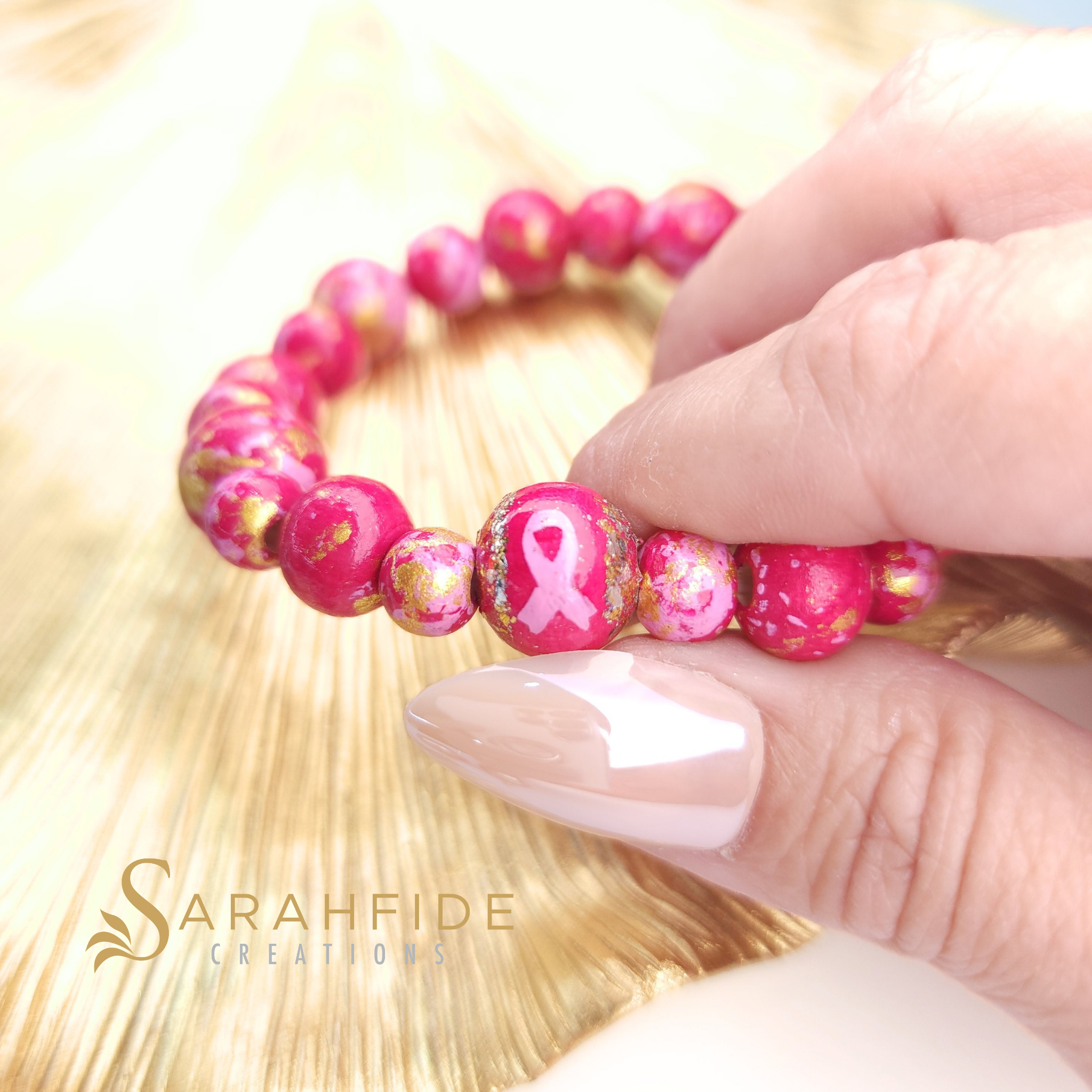 Breast Cancer Awareness Bracelet held in hand, pink ribbon bead