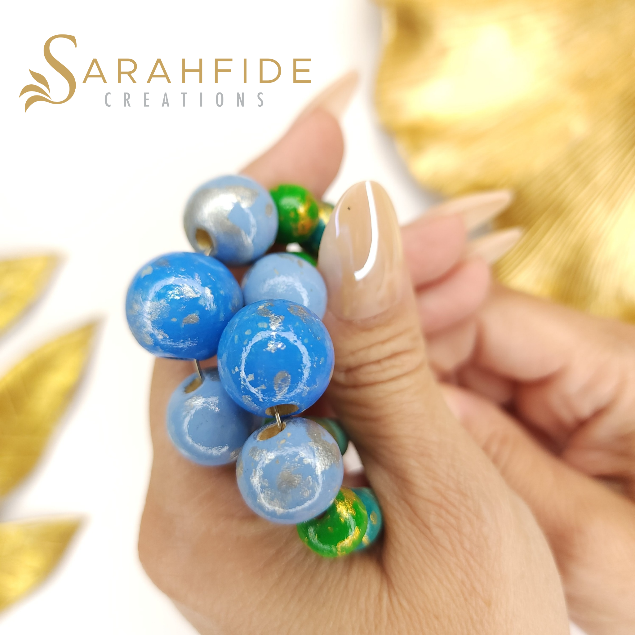 Close-up of hand-painted happy blue, French blue, teal and green wood beads in a hand