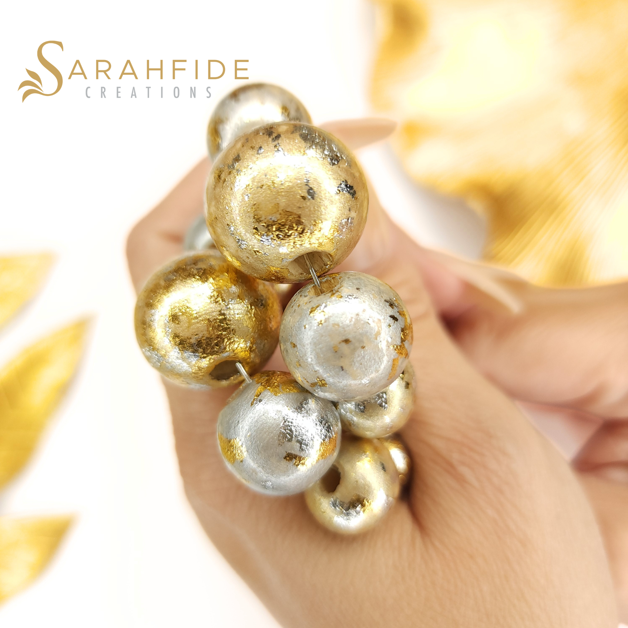 Close-up of gold and silver sparkling hand-painted wood beads held in a hand