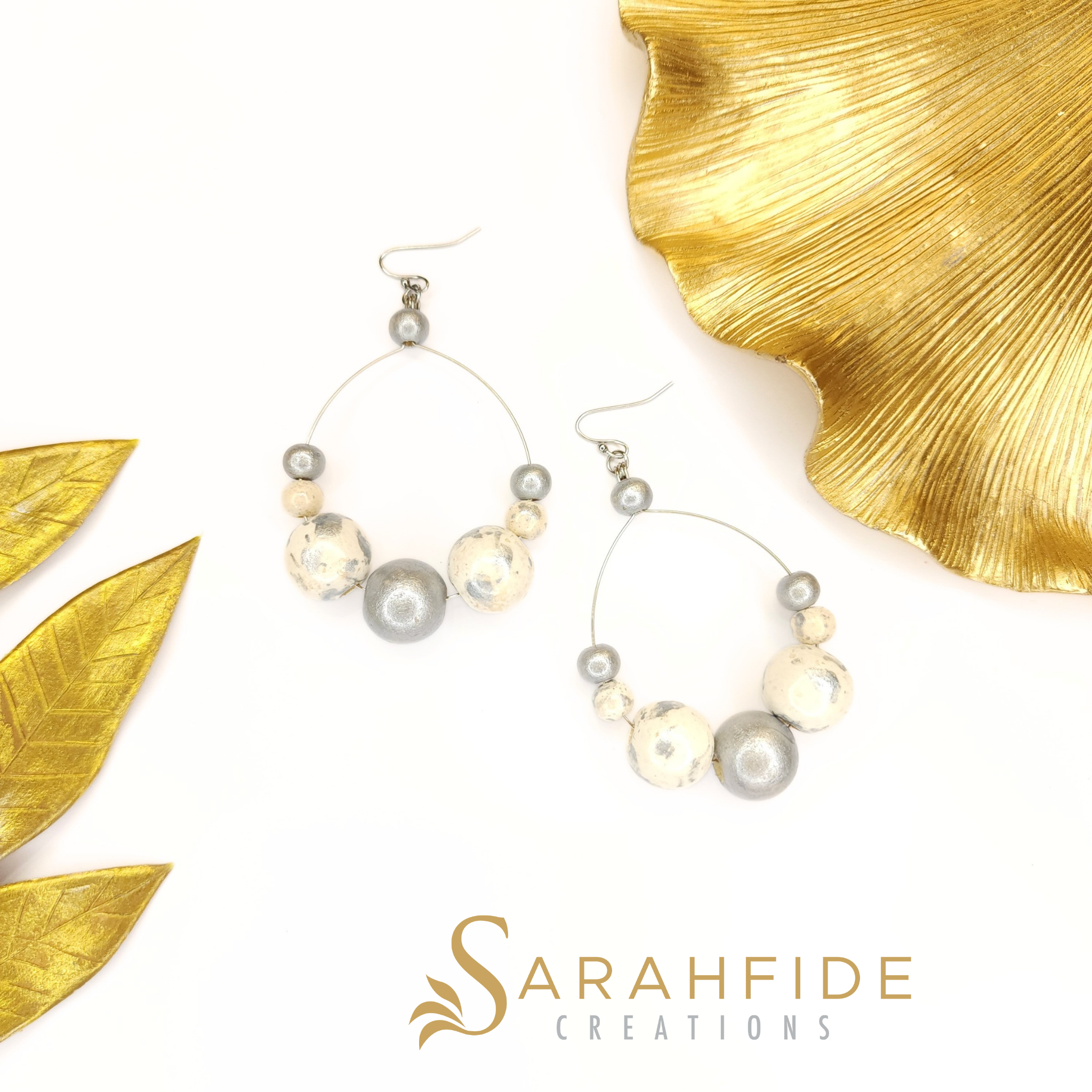 Pair of Silver Lux Large Round Drop Earrings laid flat with gold leaves