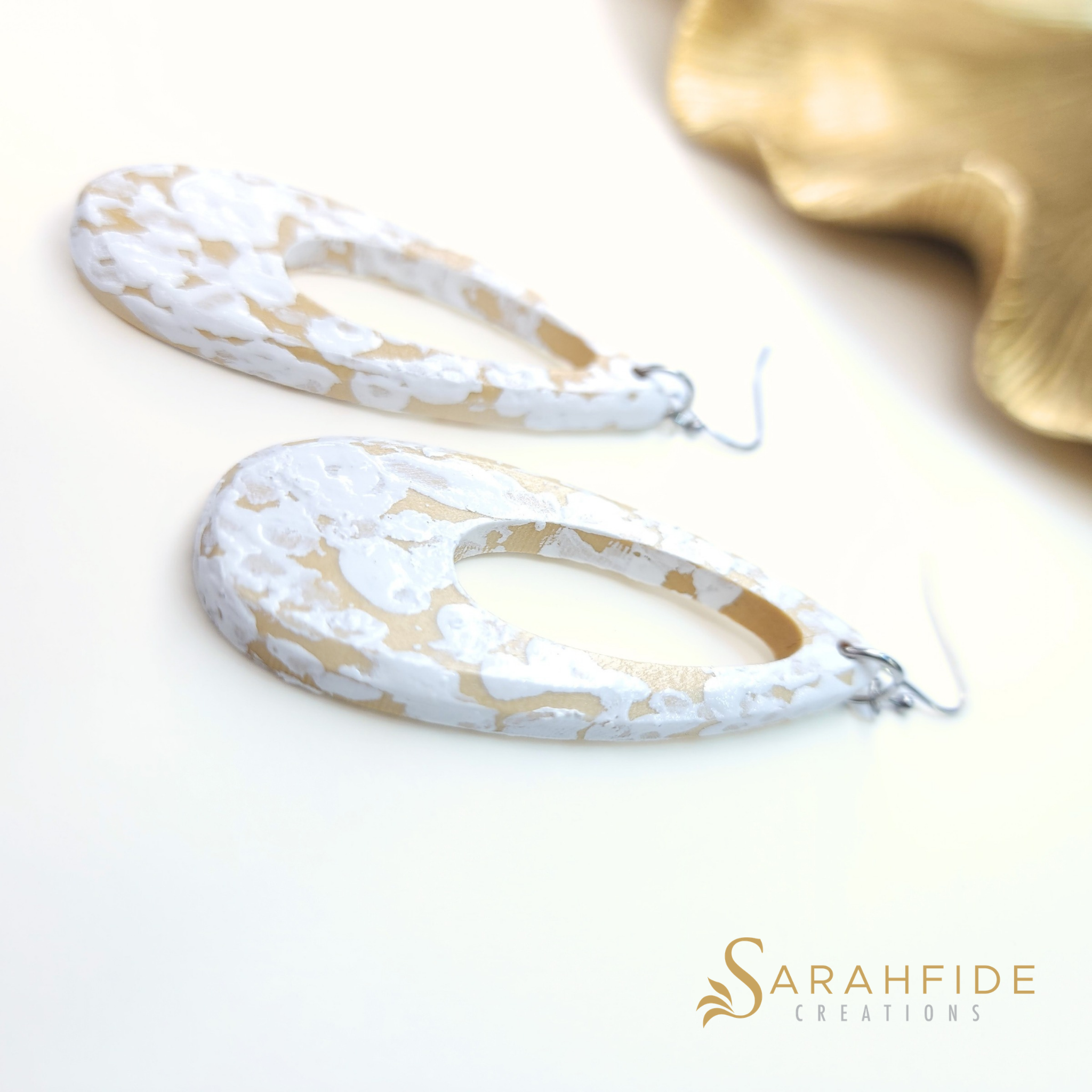 White and tan coastal drop earrings laid flat