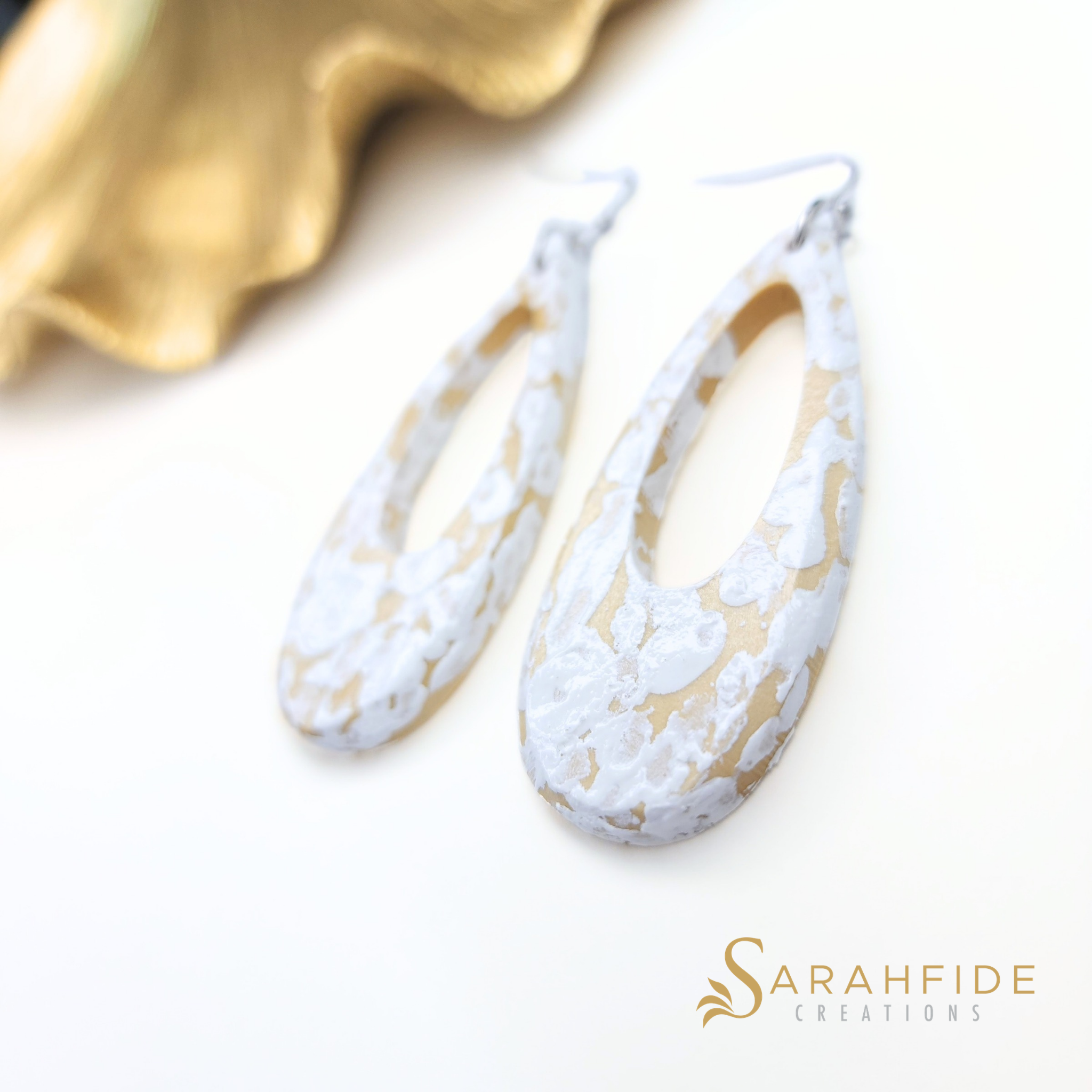 White and tan coastal drop earrings laid flat