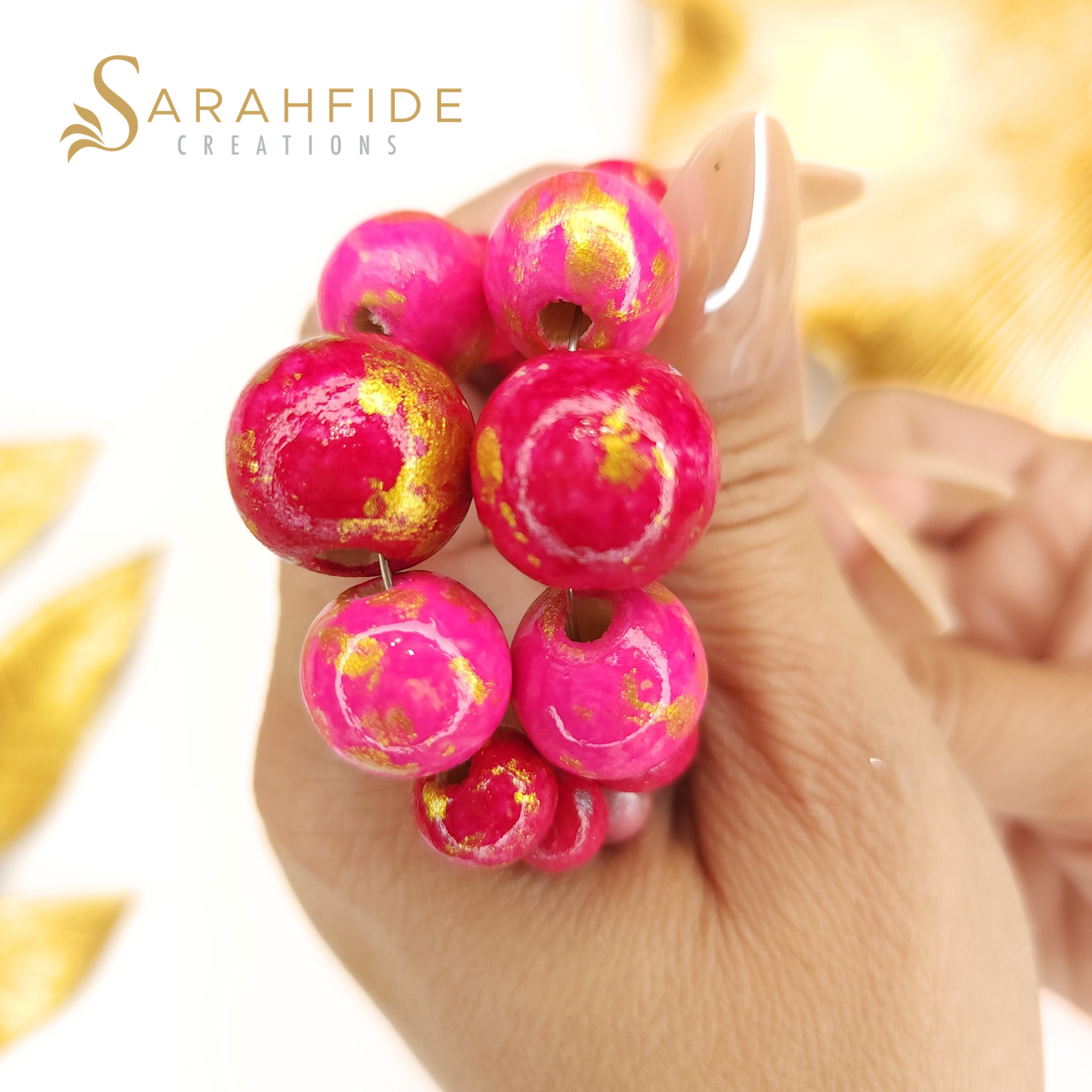 Close-up of hand-painted pink wood beads with gold and silver marbling