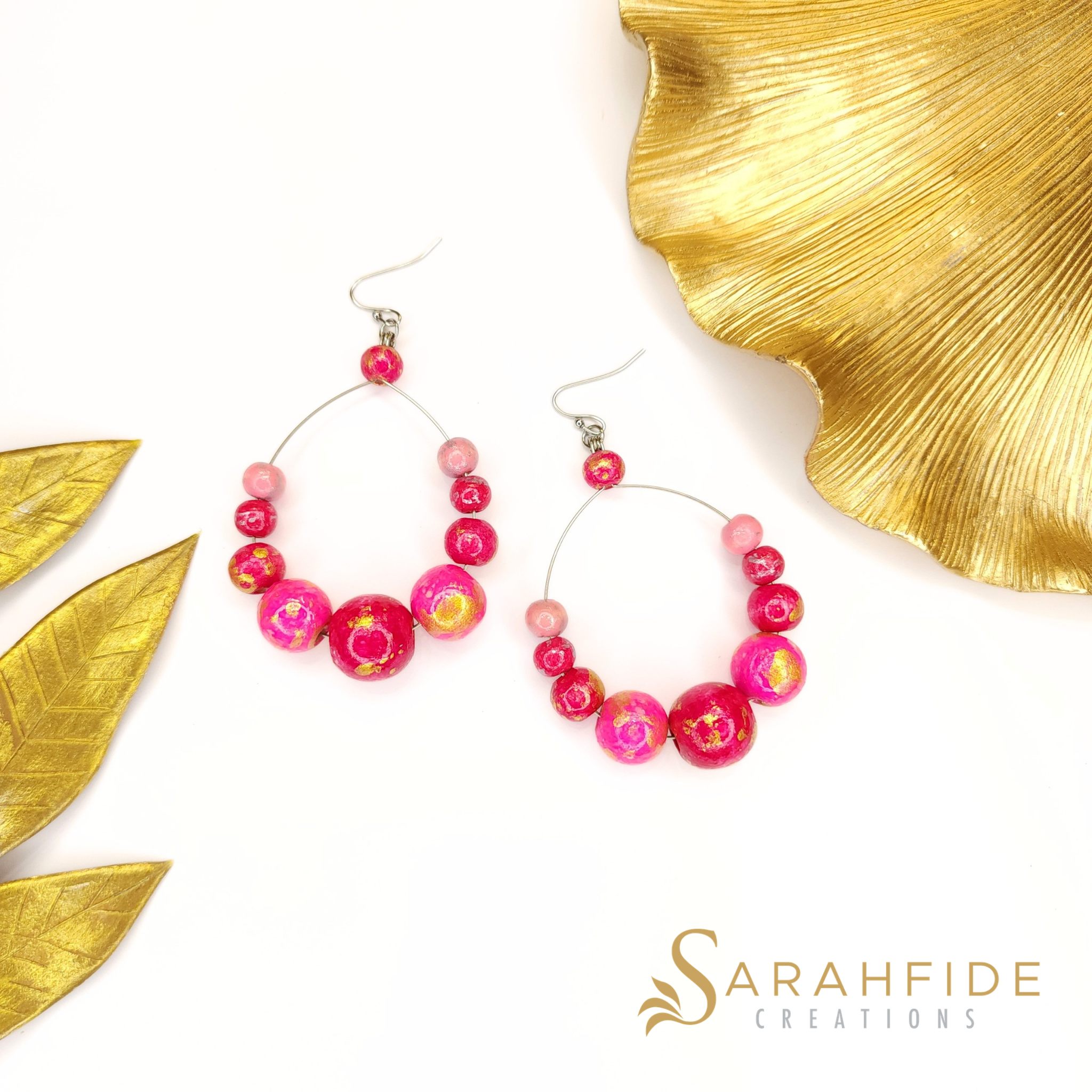 Pair of Pink Color Pop Large Round Drop Earrings laid flat with gold leaves