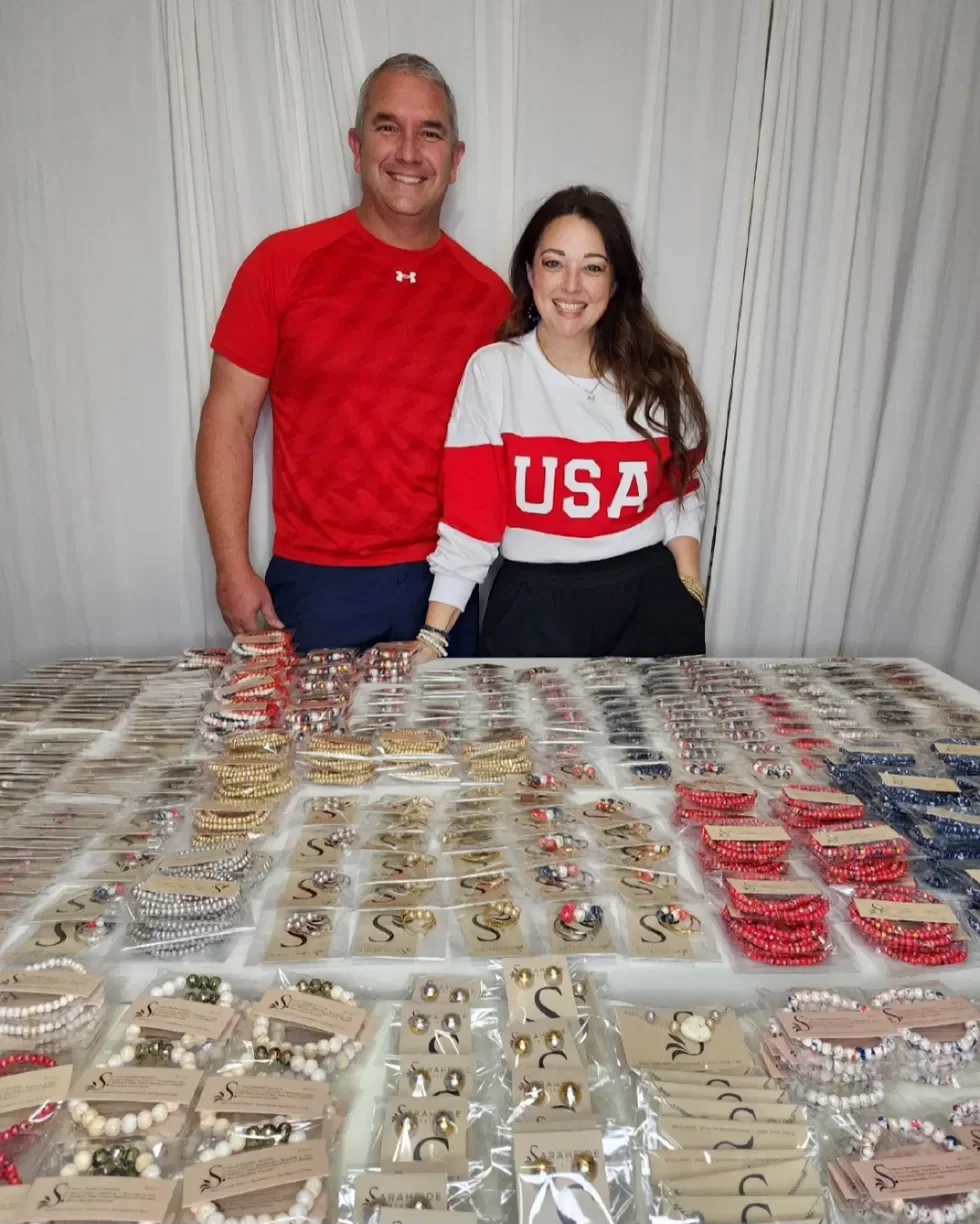 Sarah and John Cash behind a table filled with handmade red, white and blue Sarahfide jewelry.