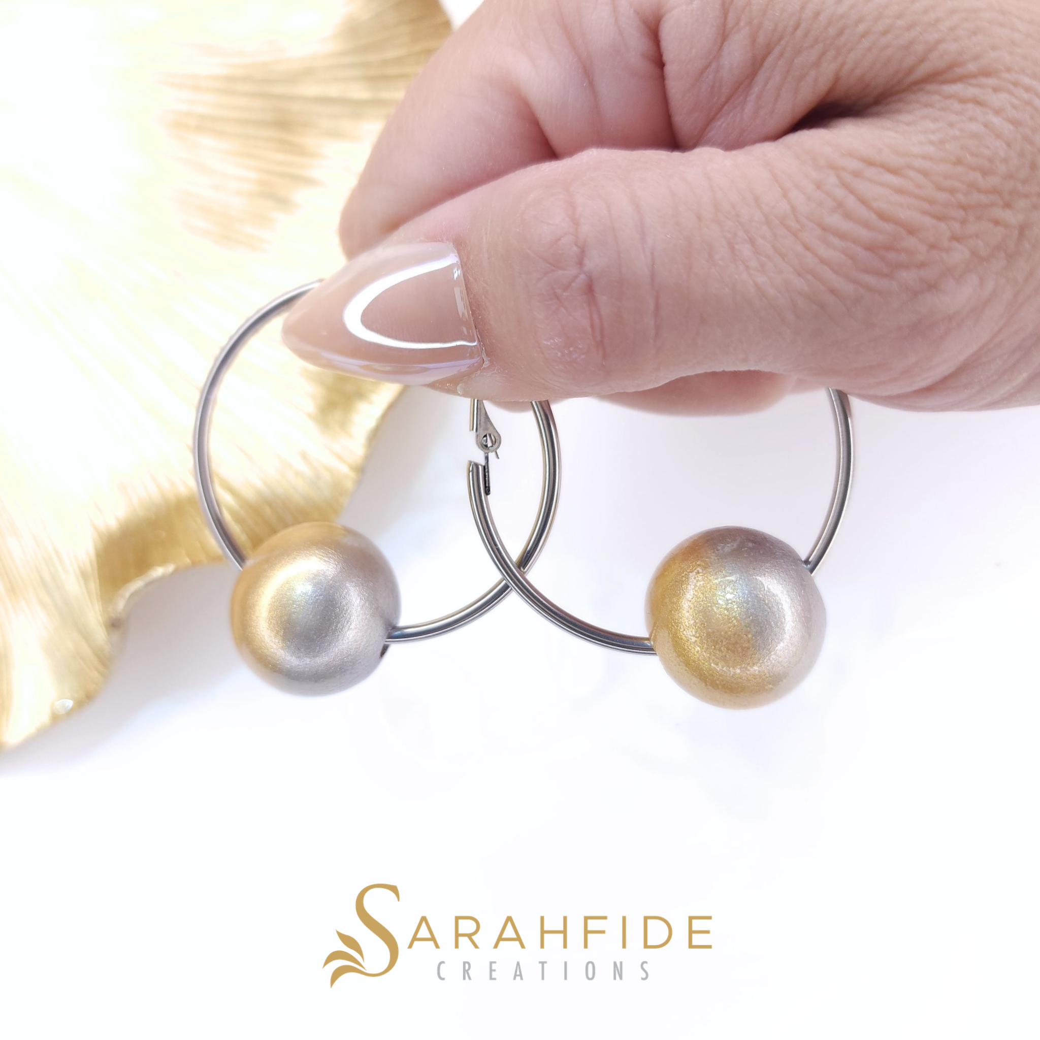 Platinum Bougie Hoop Earrings with silver hoops, held in hand