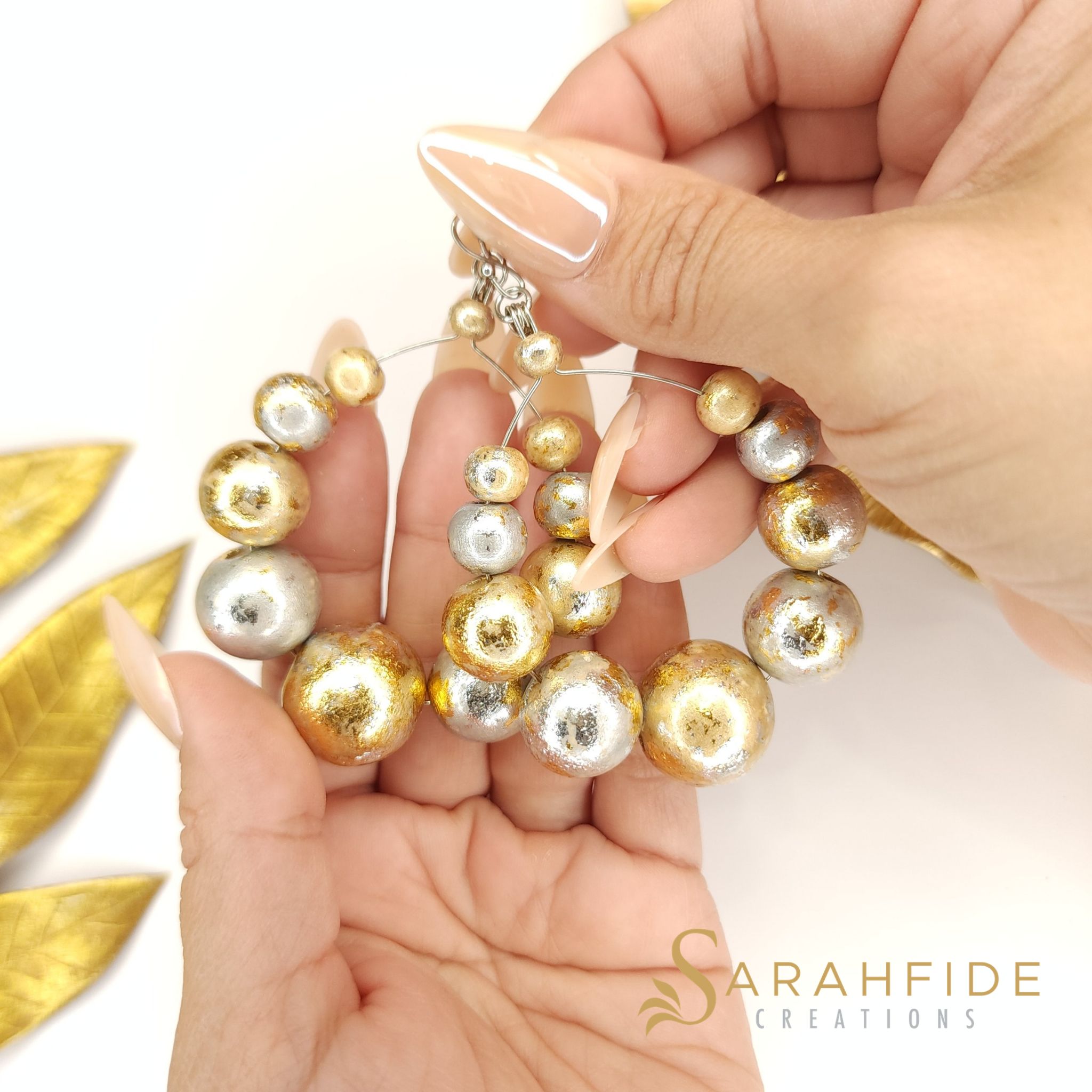 Sparkling Large Round Drop Earrings held in a hand, alternating gold and silver sparkling beads